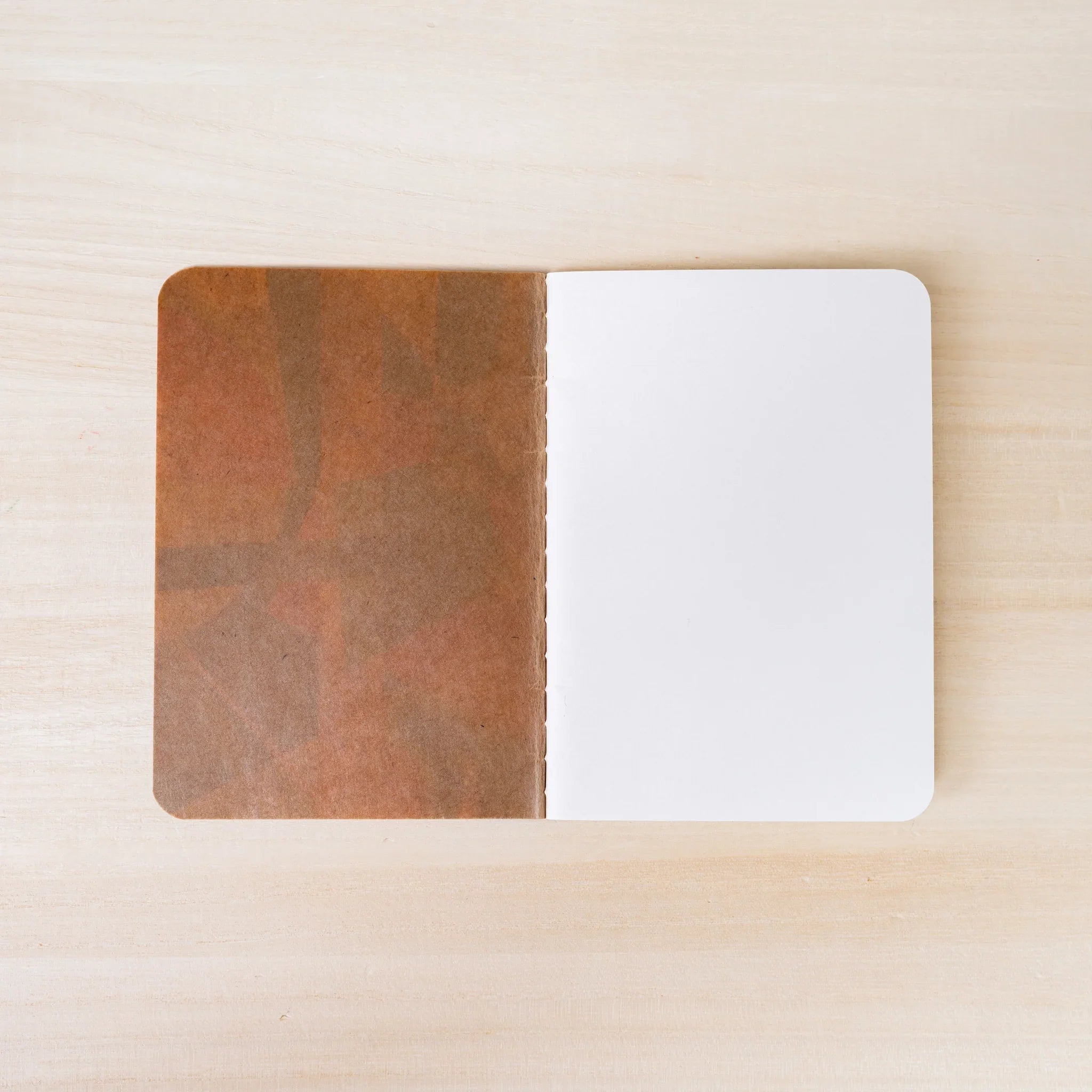RO-BIKI NOTE open flat, brown waxed kraft inner cover on left, blank white page on right, rounded corners visible