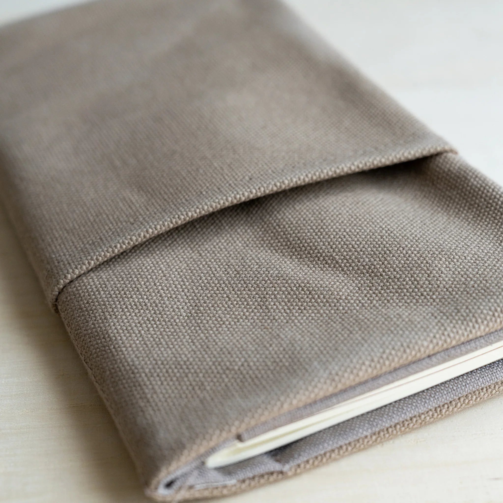 Close-up of the folded front flap and the cotton canvas weave of the RO-BIKI clay beige cover