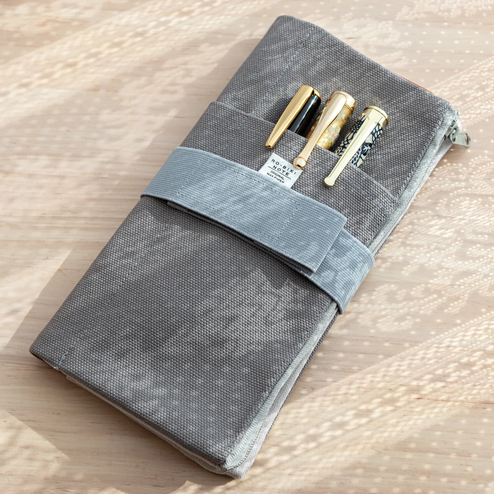 RO-BIKI Canvas Cover Cool Gray wrapped with strap, holding three fountain pens in front pocket with Japanese Note Book.