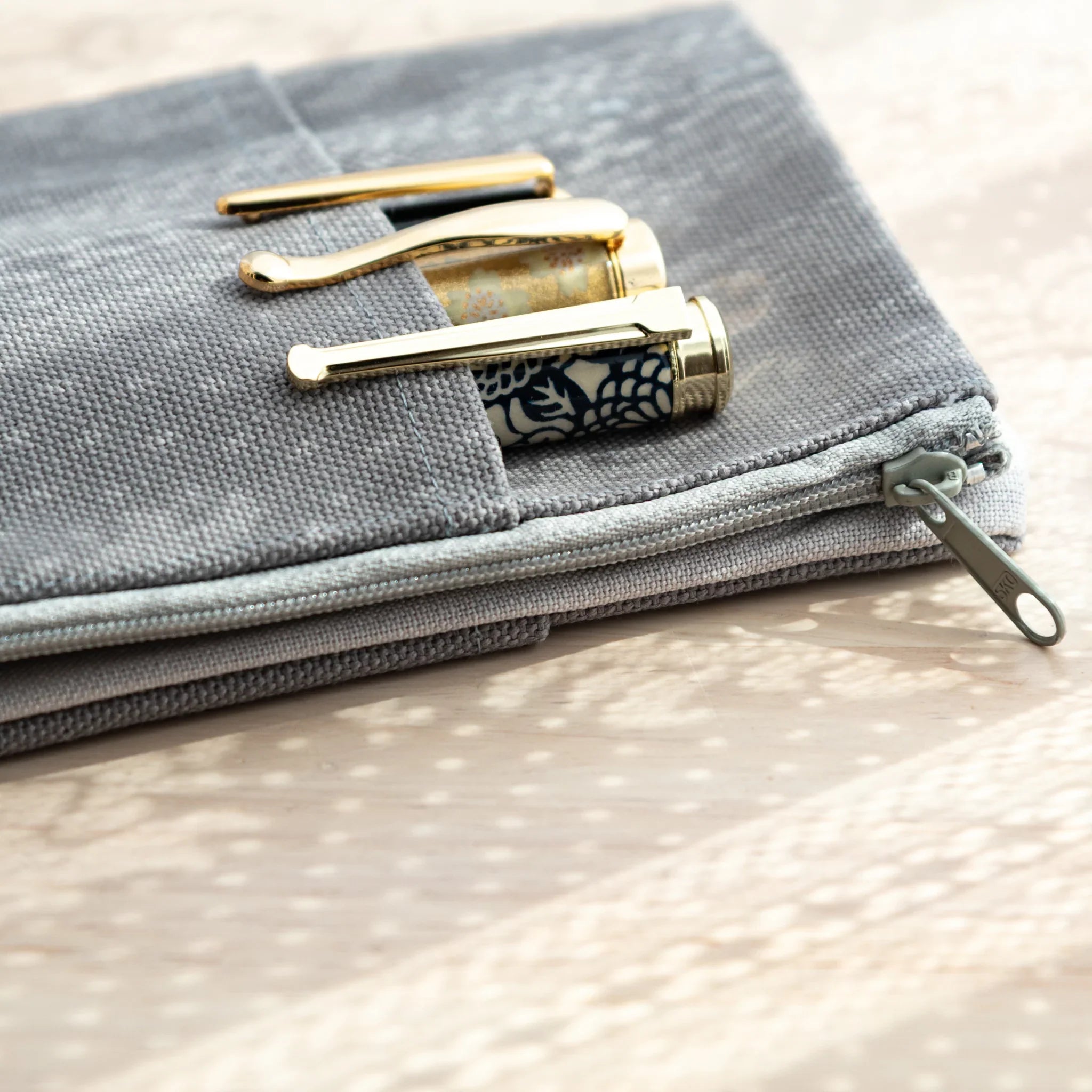 Close-up of RO-BIKI Canvas Cover Cool Gray zipper and front pen pocket with Japanese Note Book and pens.