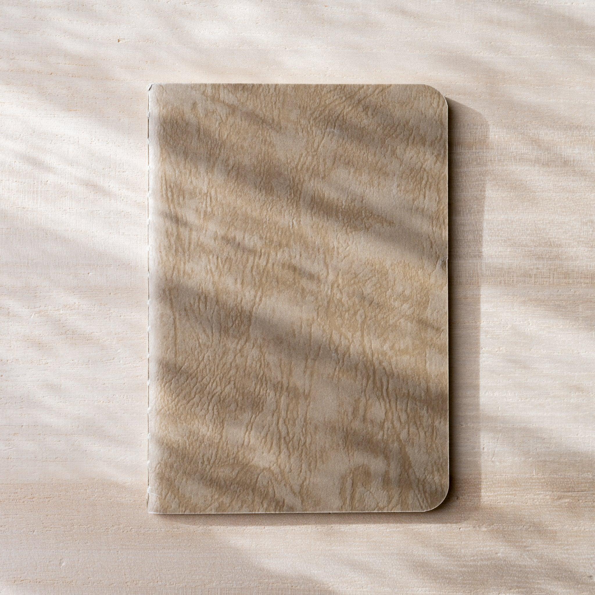 RO-BIKI NOTE open flat, brown waxed kraft inner cover on left, blank white page on right, rounded corners