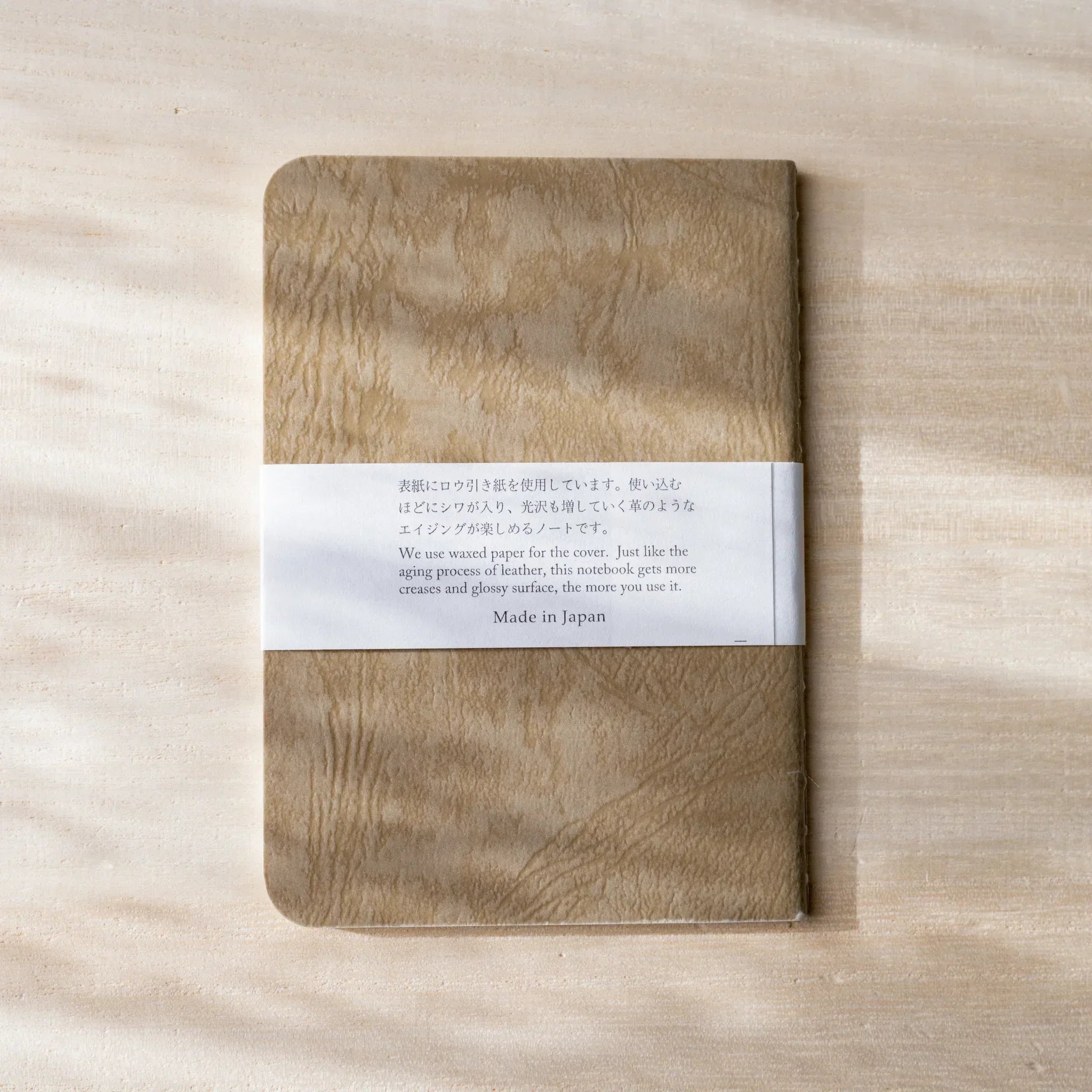 Hand peeling back corner of cream page in RO-BIKI NOTE, showing paper thickness and rounded corners detail