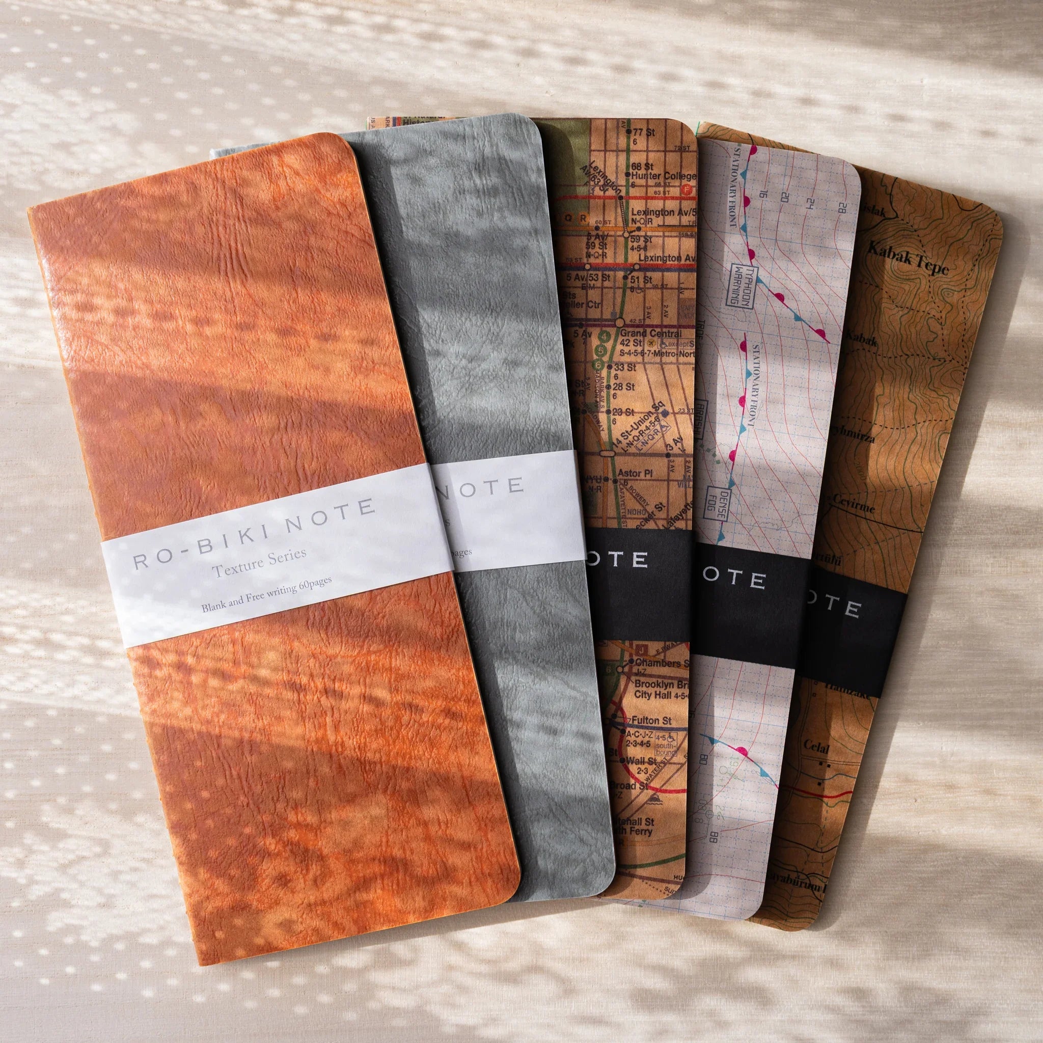 RO-BIKI NOTE collection featuring Texture Series and Map Series wax-coated notebooks in various colors fanned out