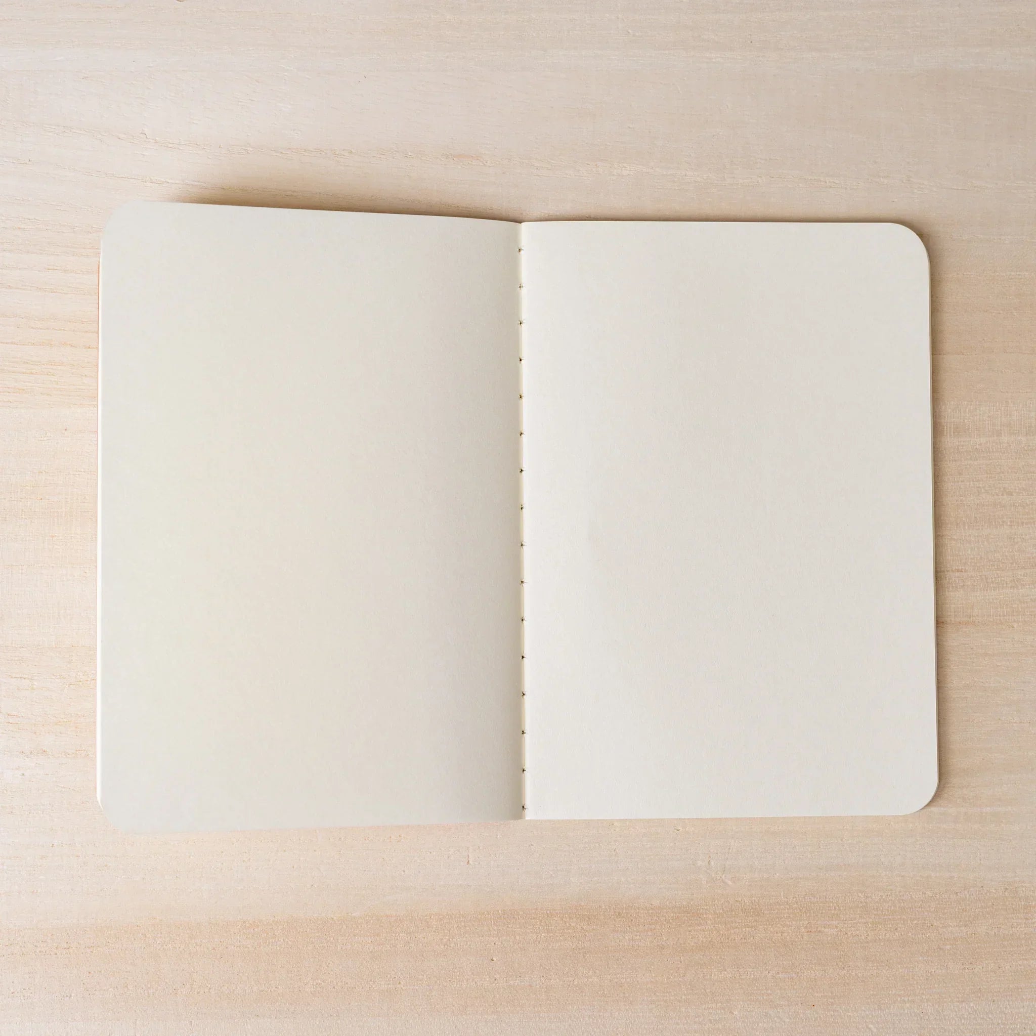 Hand peeling back corner of cream page in RO-BIKI NOTE, showing paper thickness and rounded corners detail