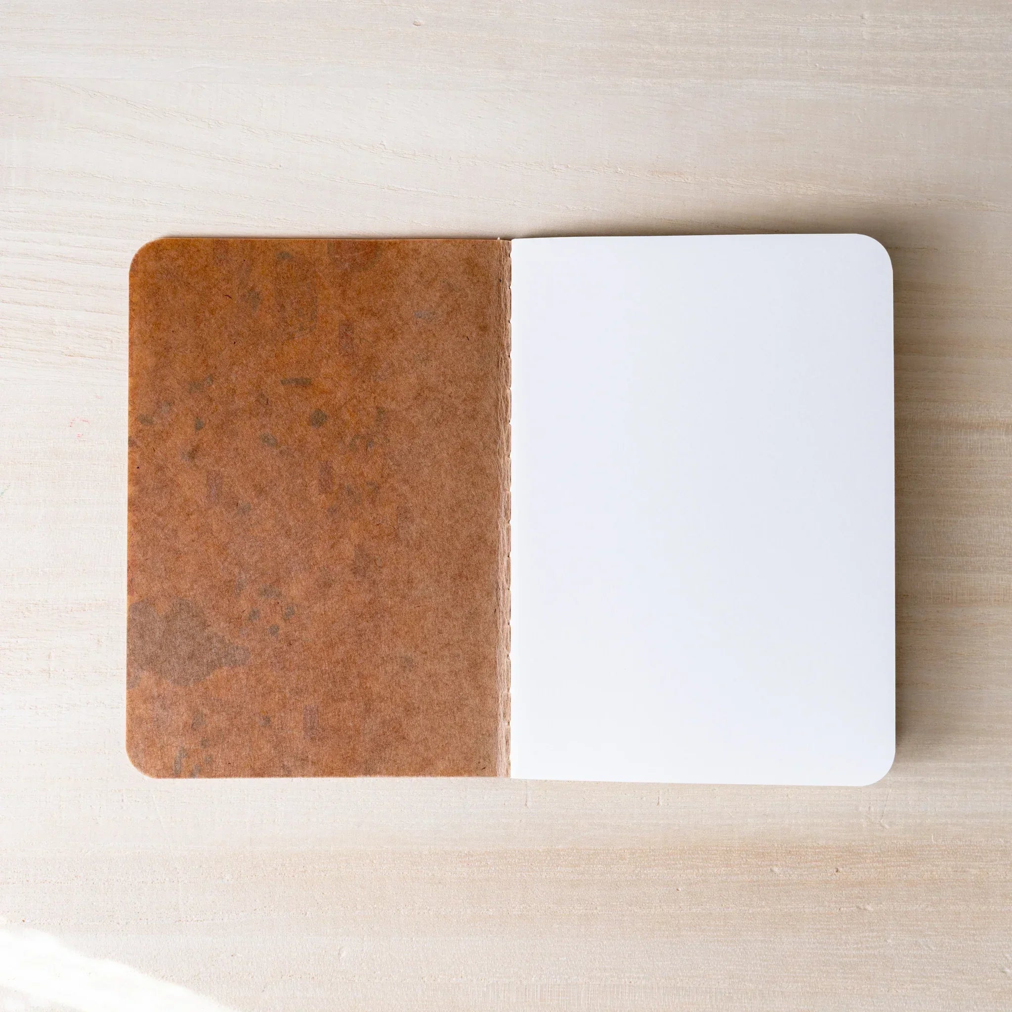 RO-BIKI NOTE open flat, brown waxed kraft inner cover on left, blank white page on right, rounded corners