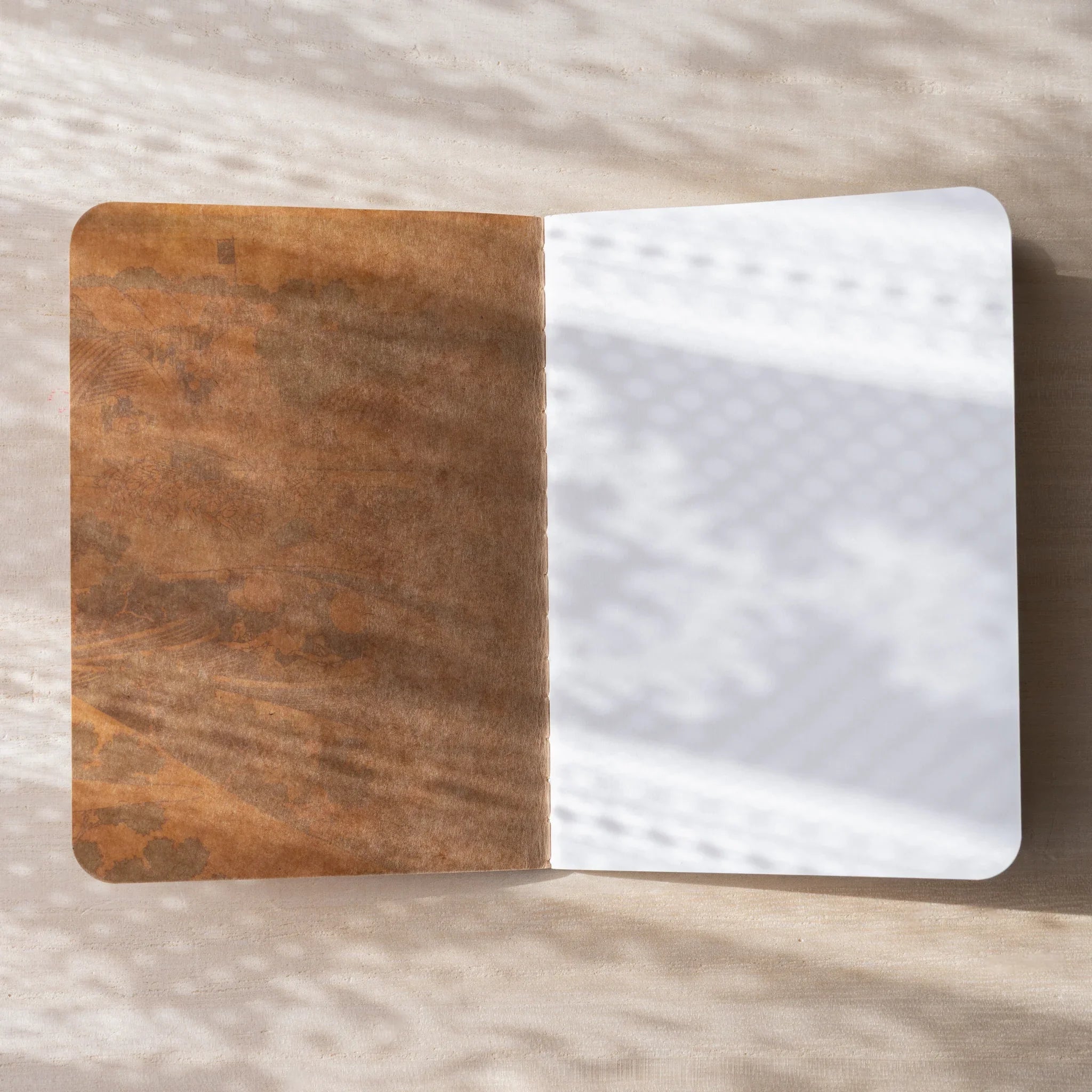 RO-BIKI NOTE open flat, brown waxed kraft inner cover on left, blank white page on right, rounded corners visible