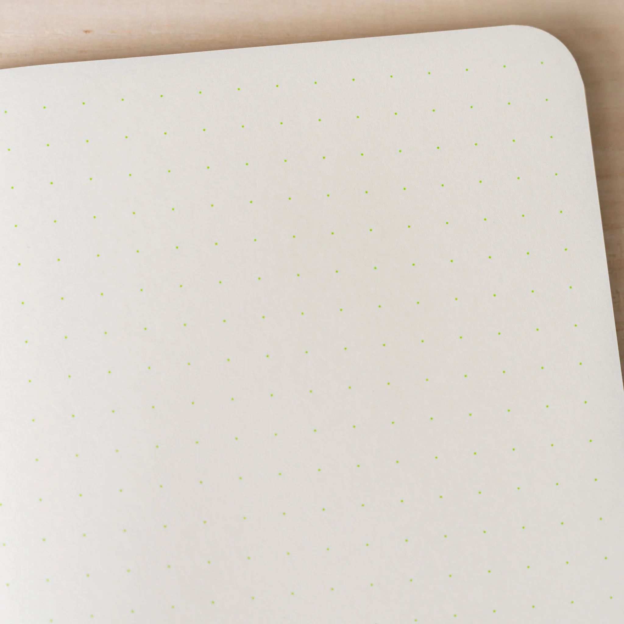 Close-up of RO-BIKI NOTE ivory dot grid page showing yellow-green 5mm dot pattern, rounded corner visible at top right