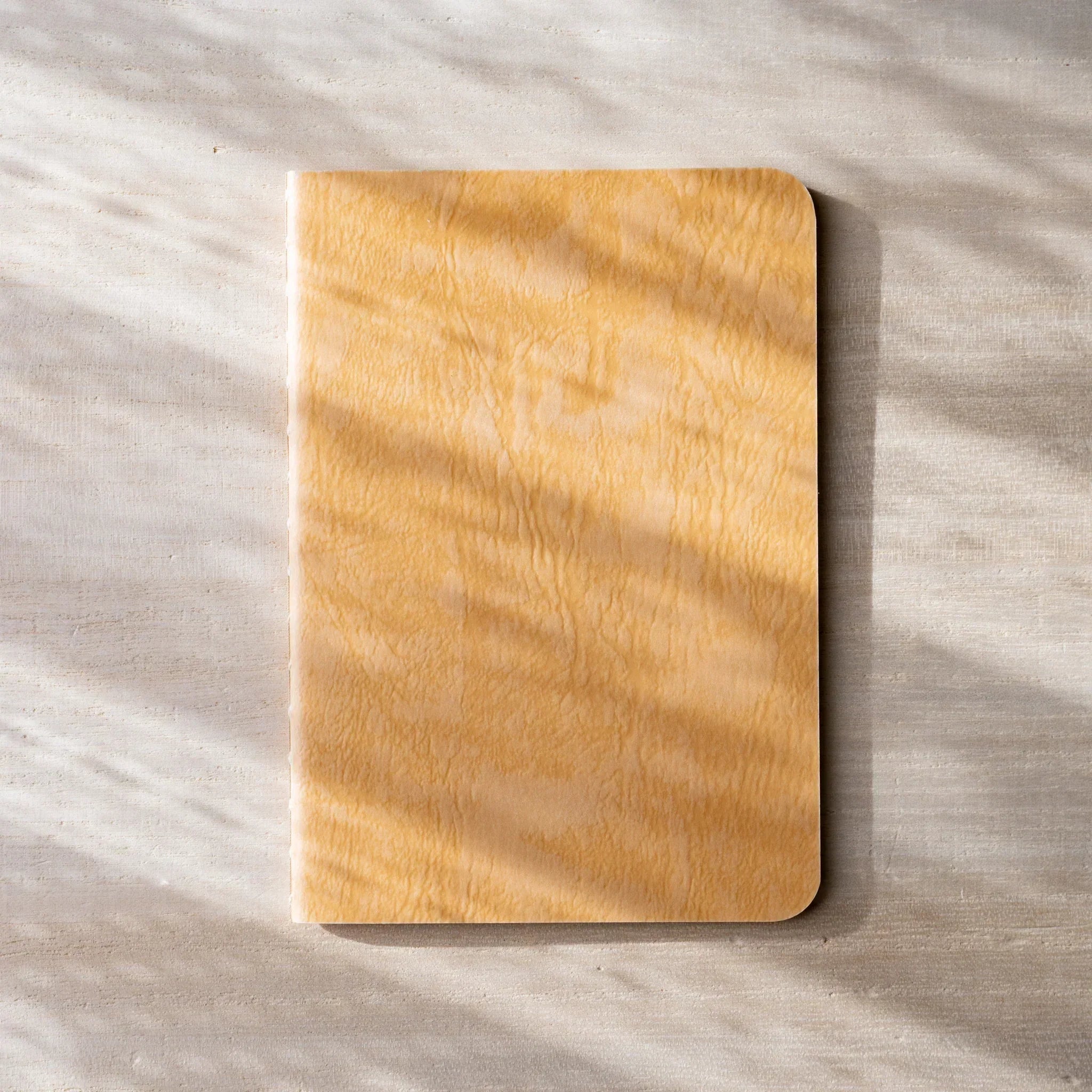 RO-BIKI NOTE open flat, brown waxed kraft inner cover on left, blank white page on right, rounded corners