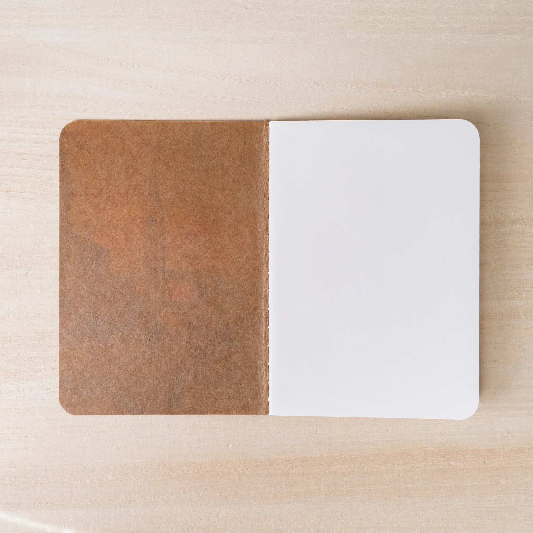 RO-BIKI NOTE open flat, brown waxed kraft inner cover on left, blank white page on right, rounded corners visible