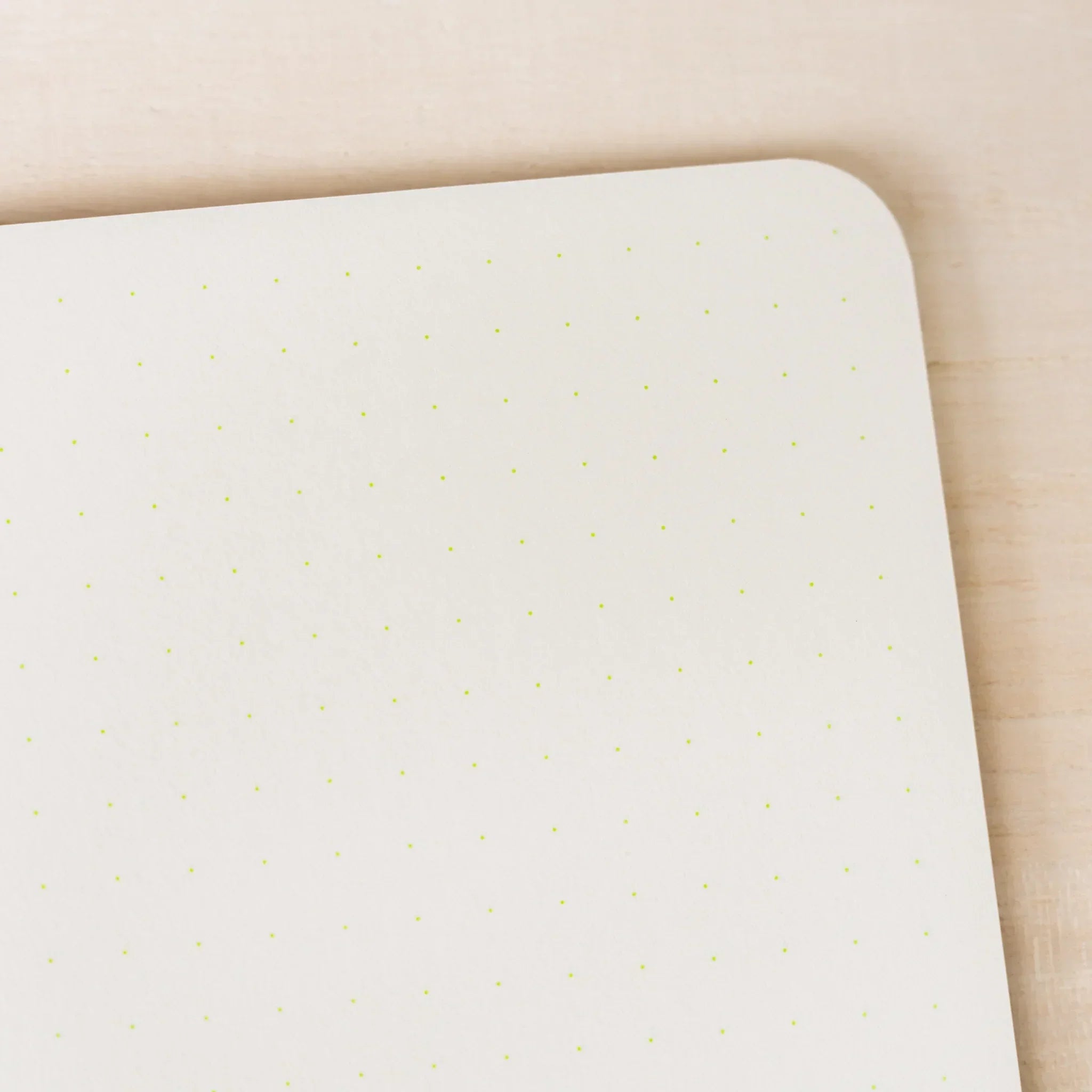 Close-up of RO-BIKI NOTE ivory dot grid page showing yellow-green 5mm dot pattern, rounded corner visible at top right