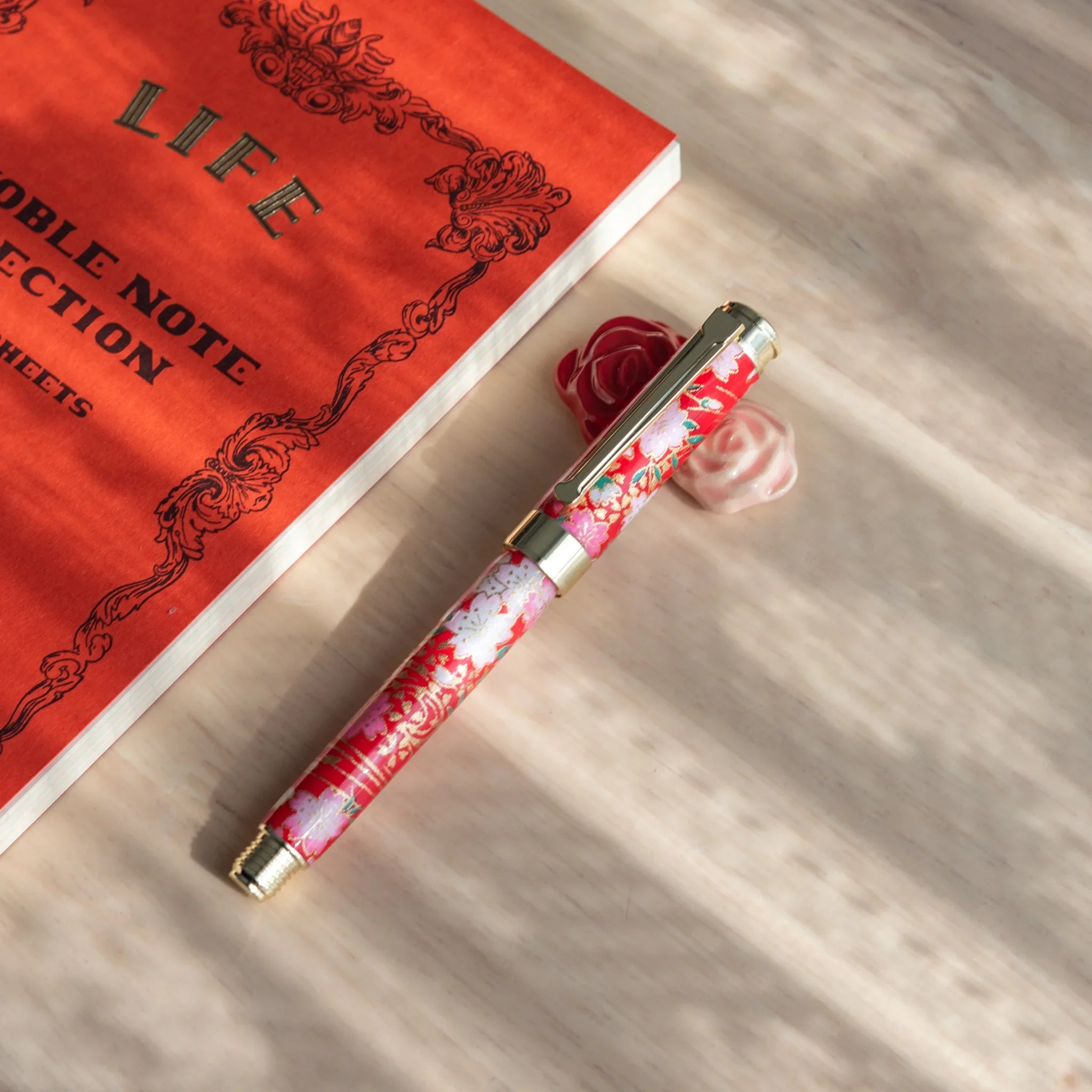 White and red rose handcrafted ceramic pen rests in decorative arrangement with green foliage leaf support detail