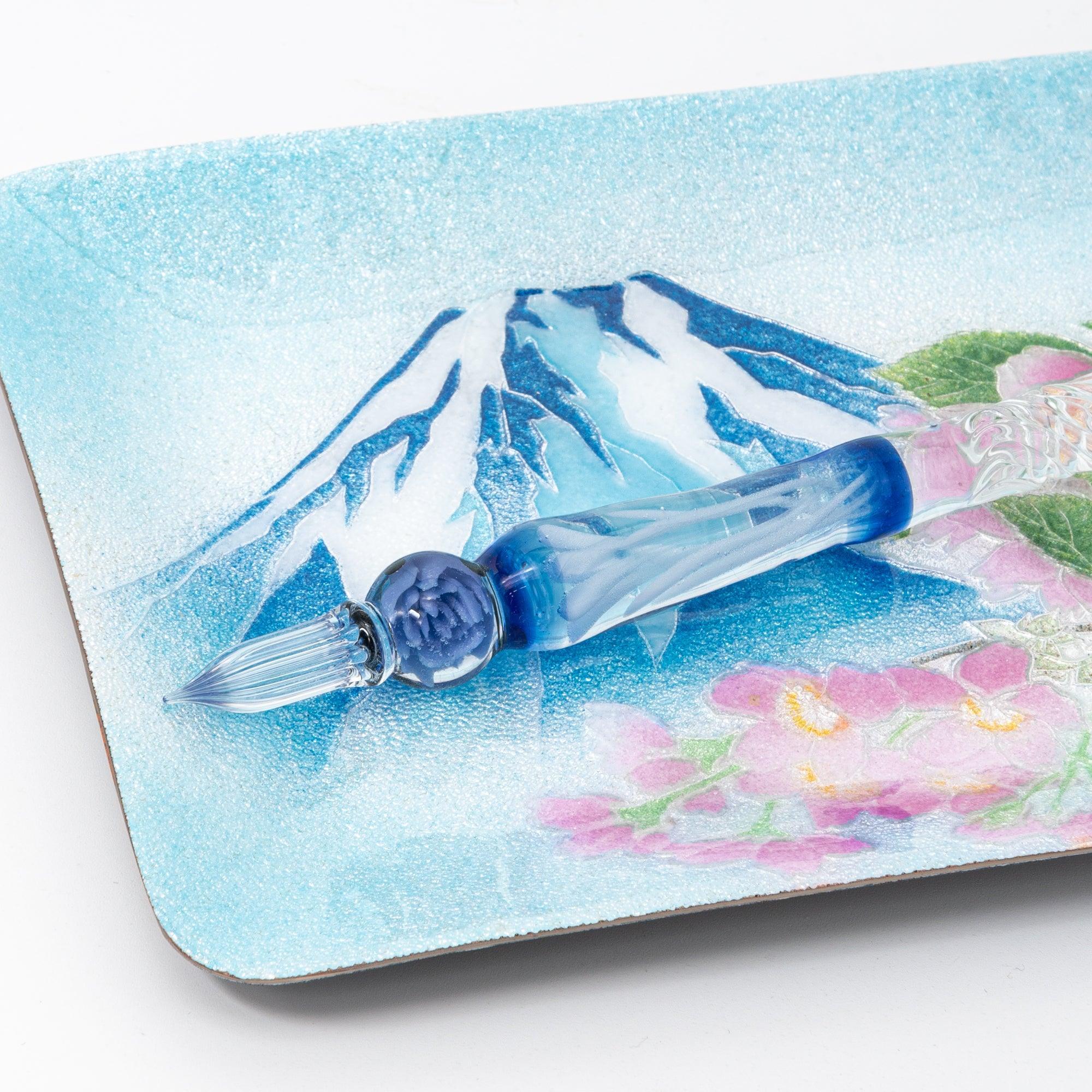 Close-up of Japanese shippo ware pen tray with Mt. Fuji design, blue gradient glass dip pen with bead handle resting inside