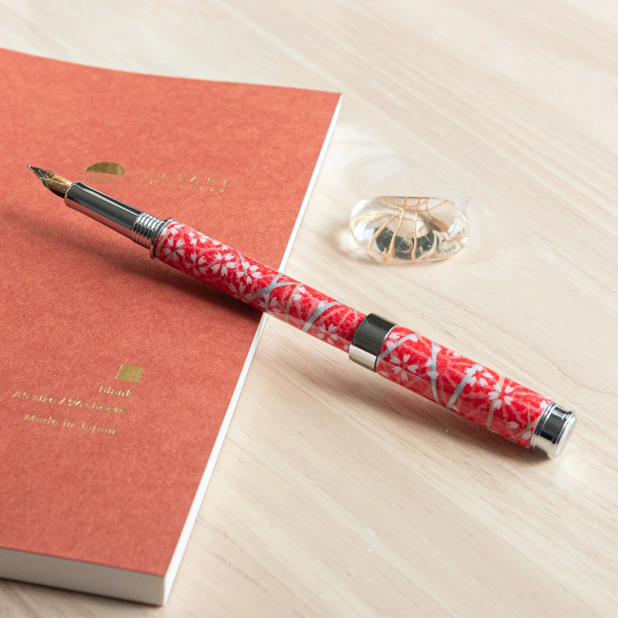 Sakura and Hemp Leaves Mino Washi fountain pen displayed on red fabric with white hemp leaf botanical pattern nib