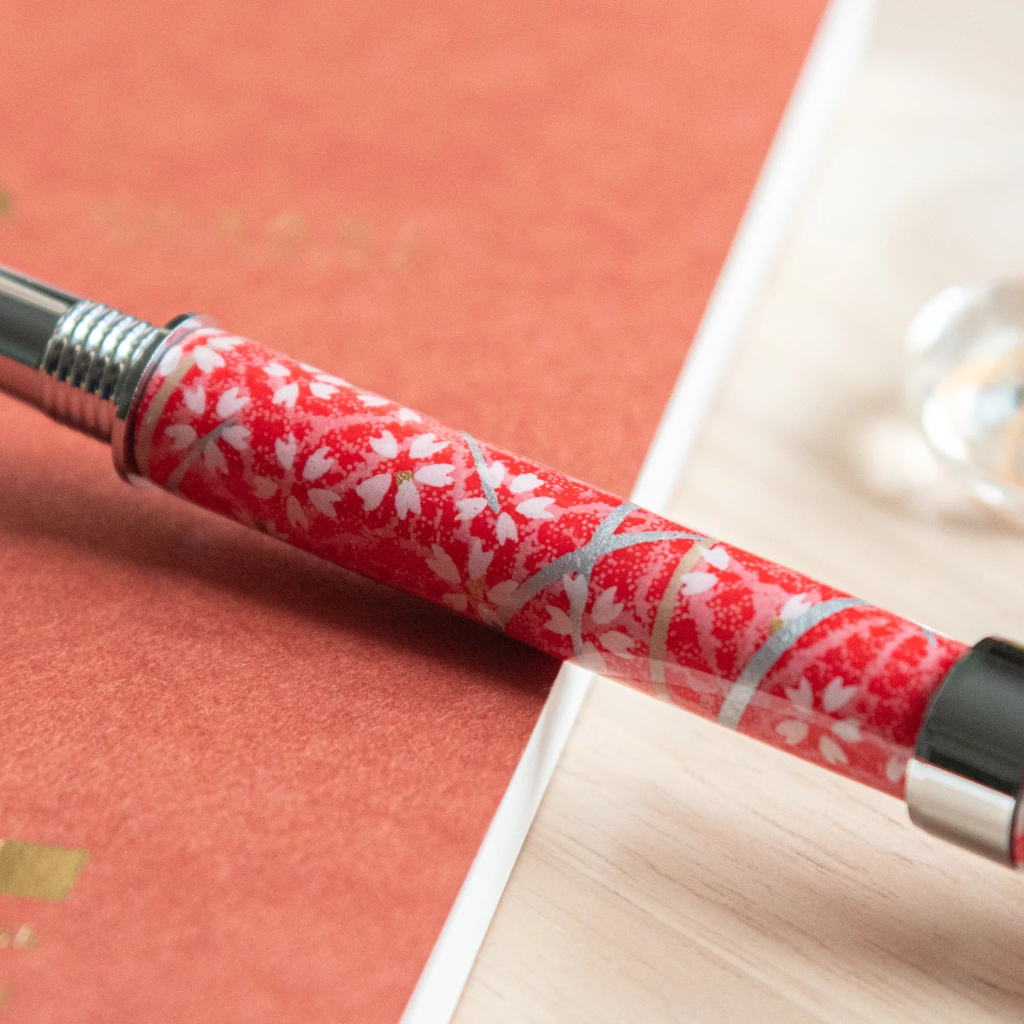 Sakura and Hemp Leaves Mino Washi fountain pen close-up showing red wrap with white cherry blossom and green leaf patterns