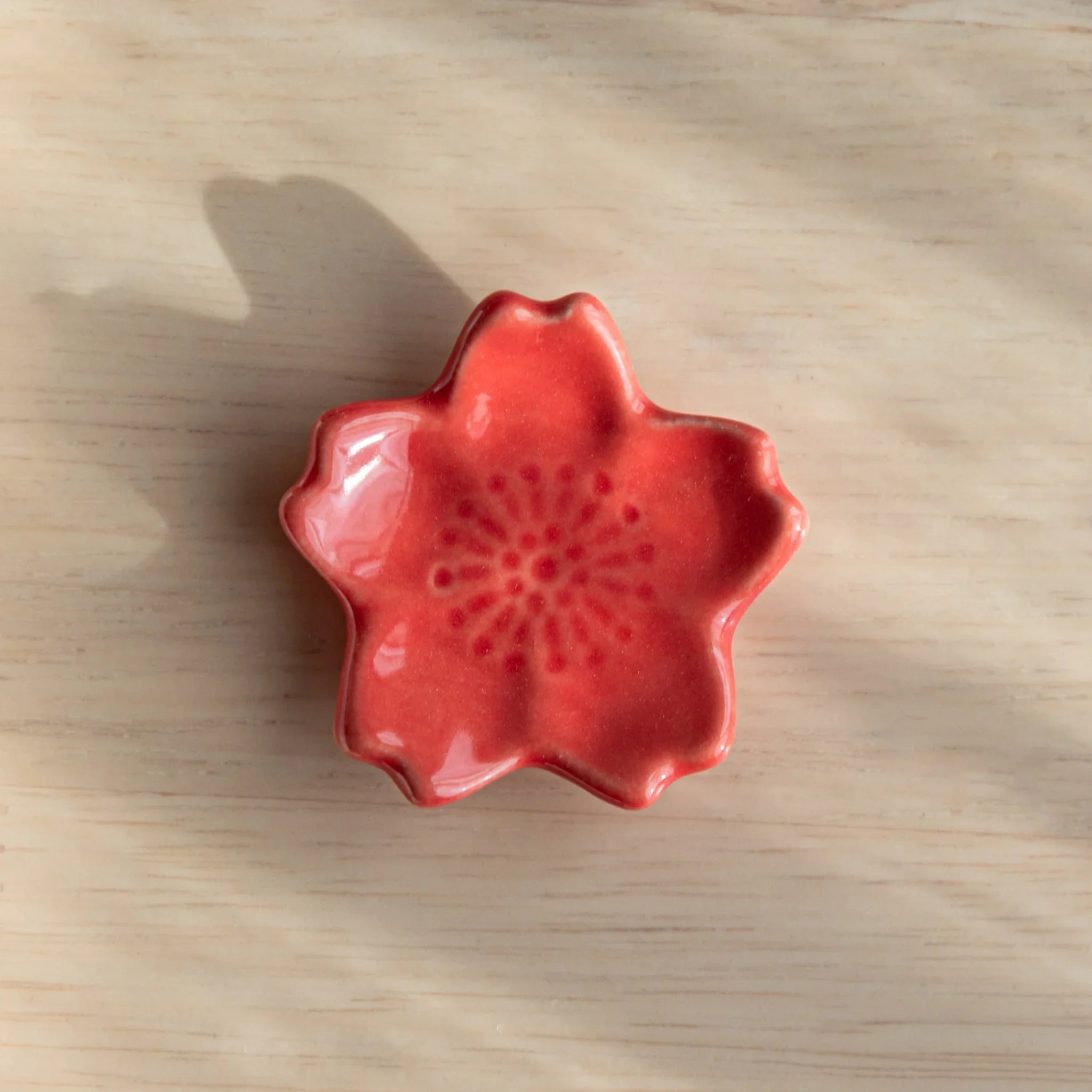 Pale pink sakura flower handcrafted pen rest displaying five individual sculptured petal surface details on neutral surface