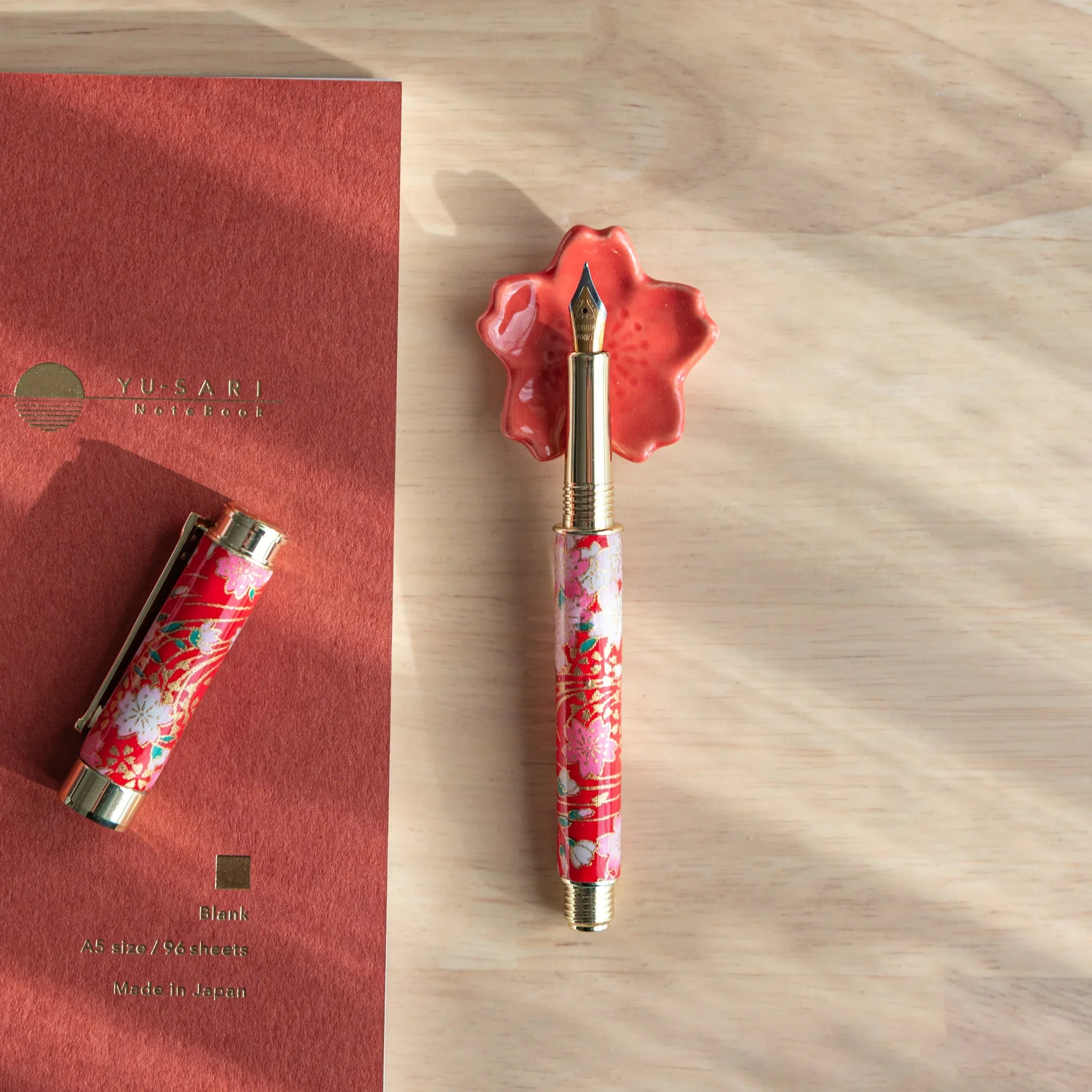 Light pink cherry blossom ceramic pen rest with petal relief texture and smooth central functional groove detail