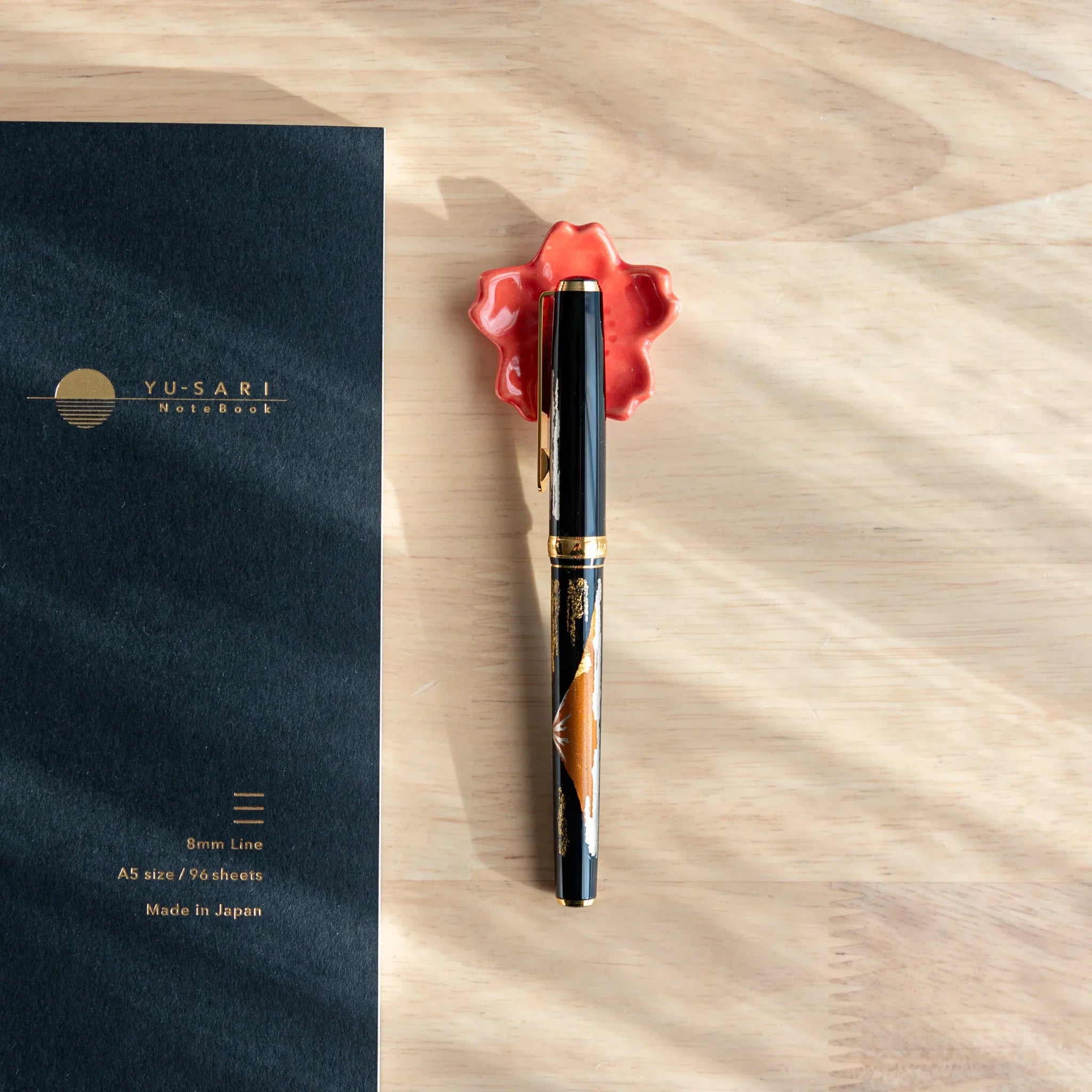 Soft pink sakura-shaped Japanese handcrafted ceramic pen rest with sculpted petals throughout design close shot