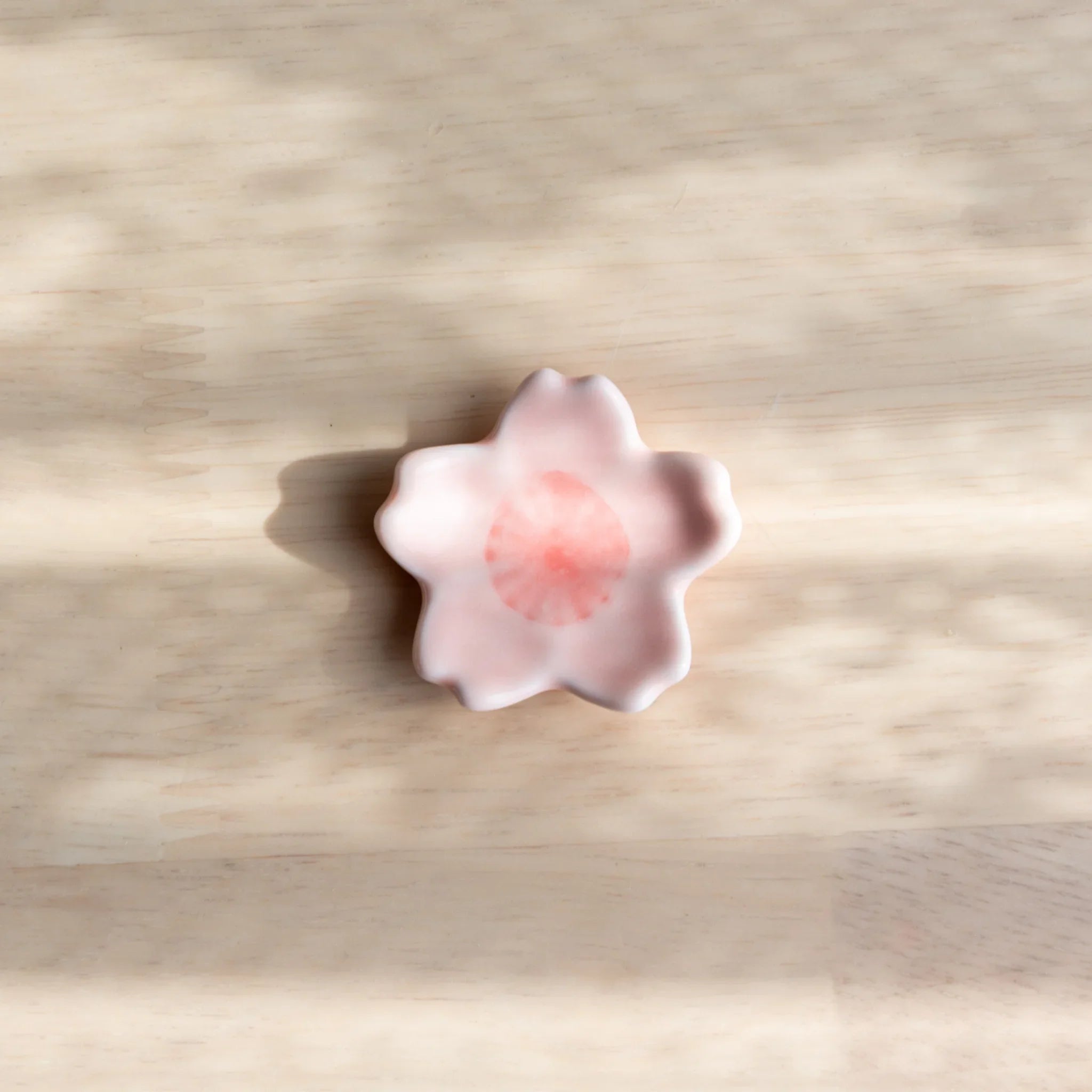 Pink sakura shaped pen rest with detailed carved flower petals showing delicate cherry blossom form structure completely