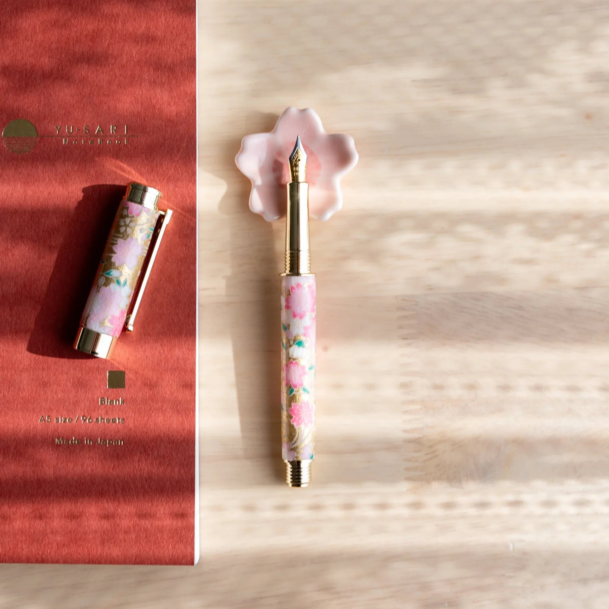 Sakura flower pen rest with delicate pink petals and stamen showing detailed flower carving and Japanese spring season theme