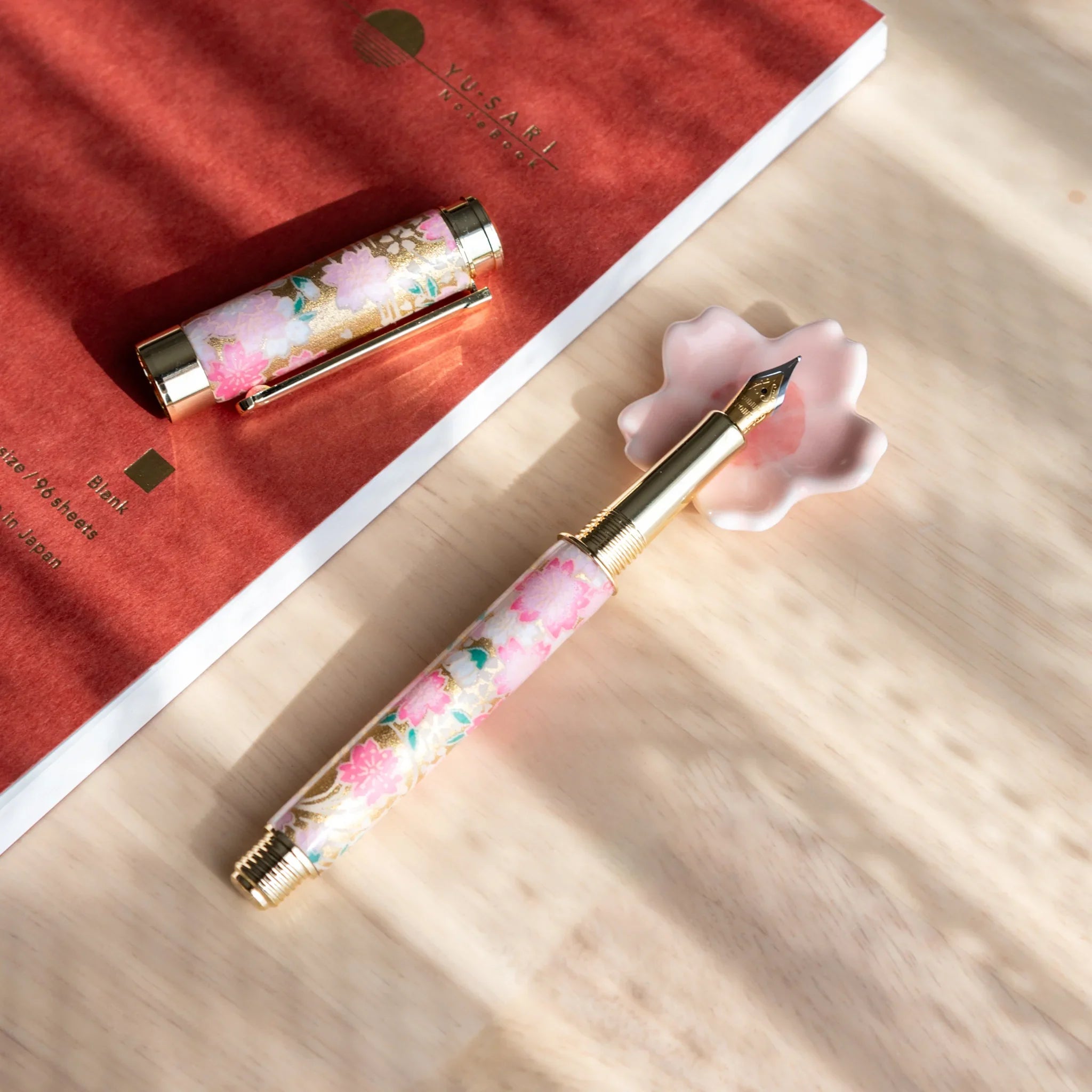 Pink cherry blossom sakura handcrafted Japanese pen rest with six-petal detailed flower form showing spring aesthetic design