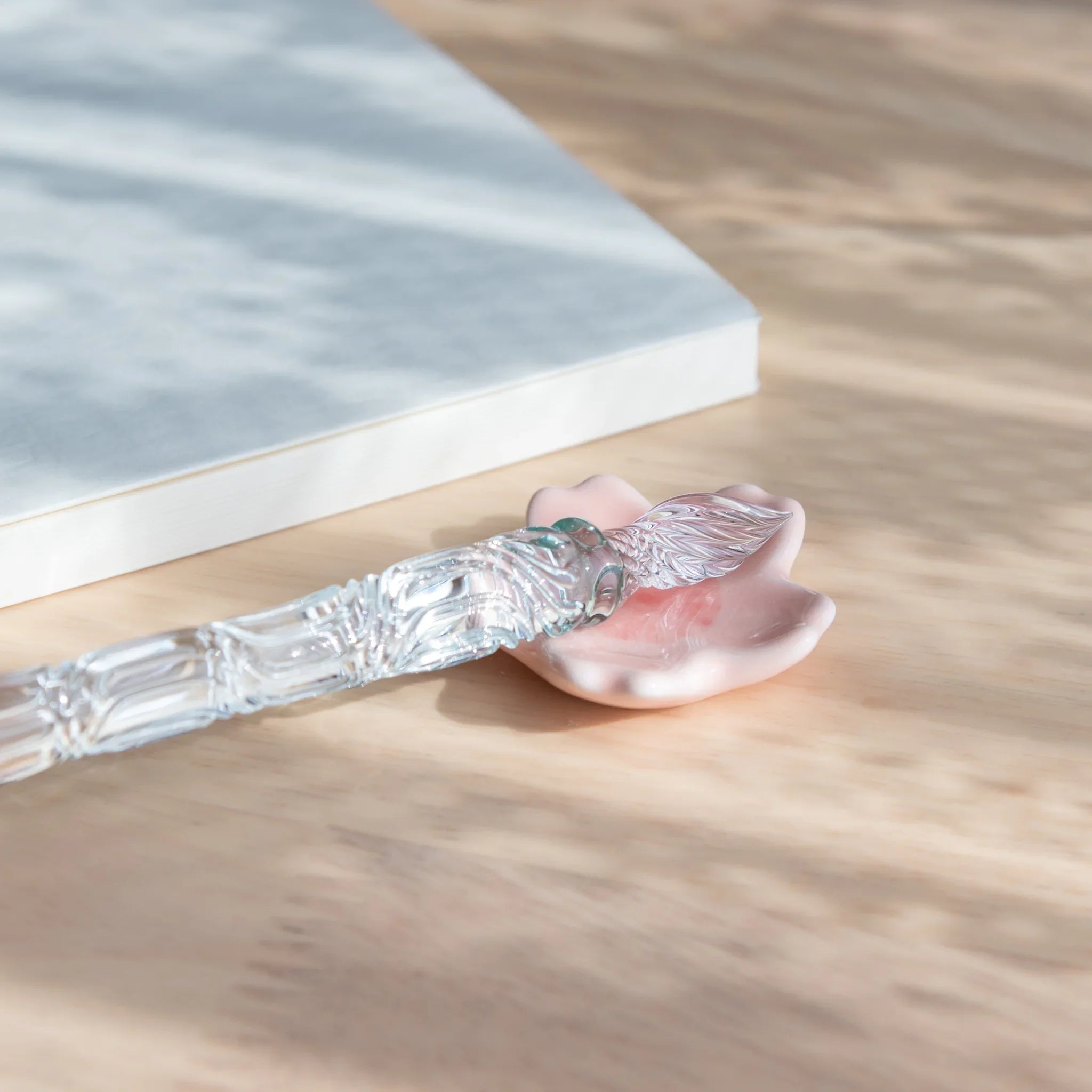 Pink handcrafted sakura-shaped ceramic pen rest with five delicate petals and central pen groove detail close shot