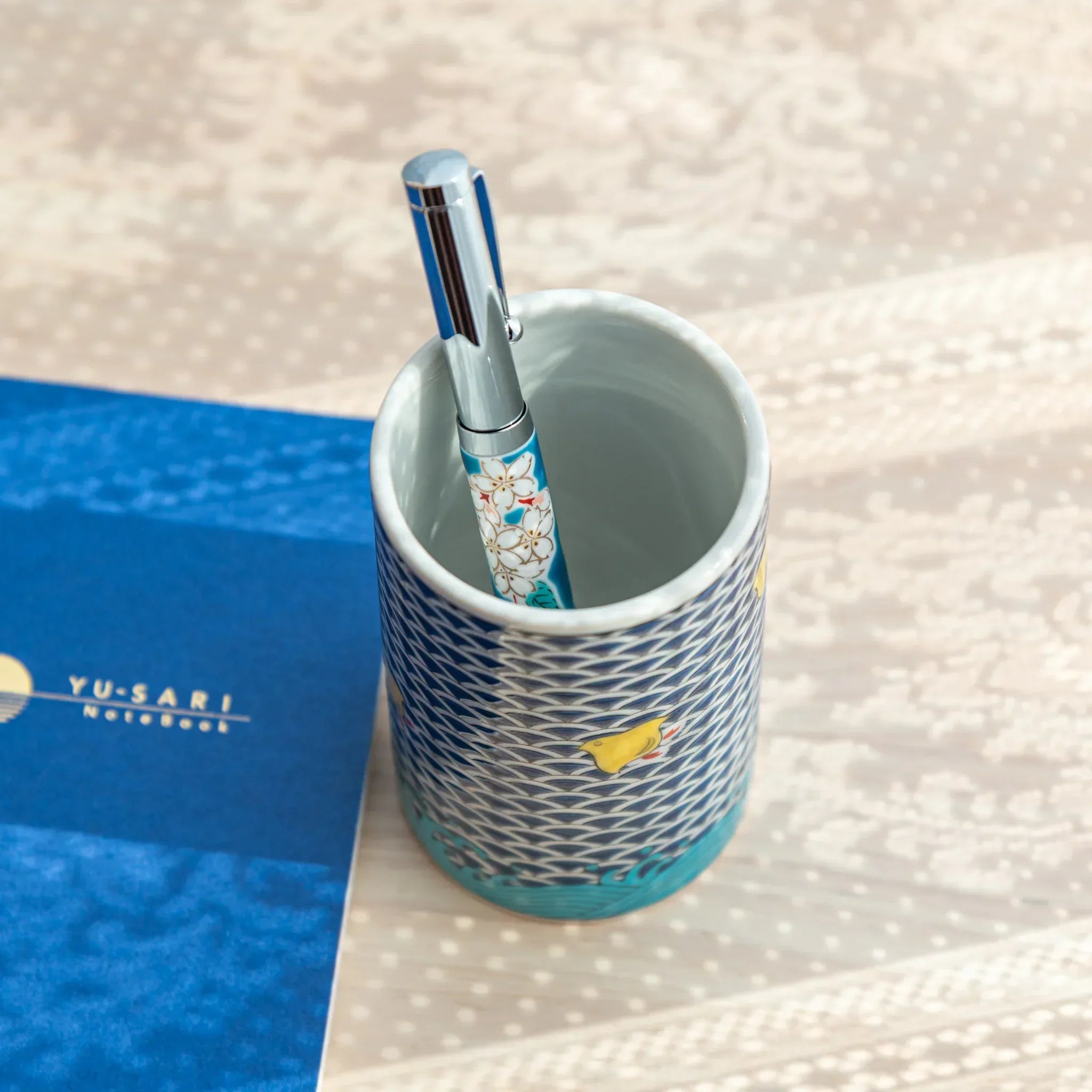 Japanese Ballpoint Pen with Sakura Kutani design standing inside matching ceramic pen holder.
