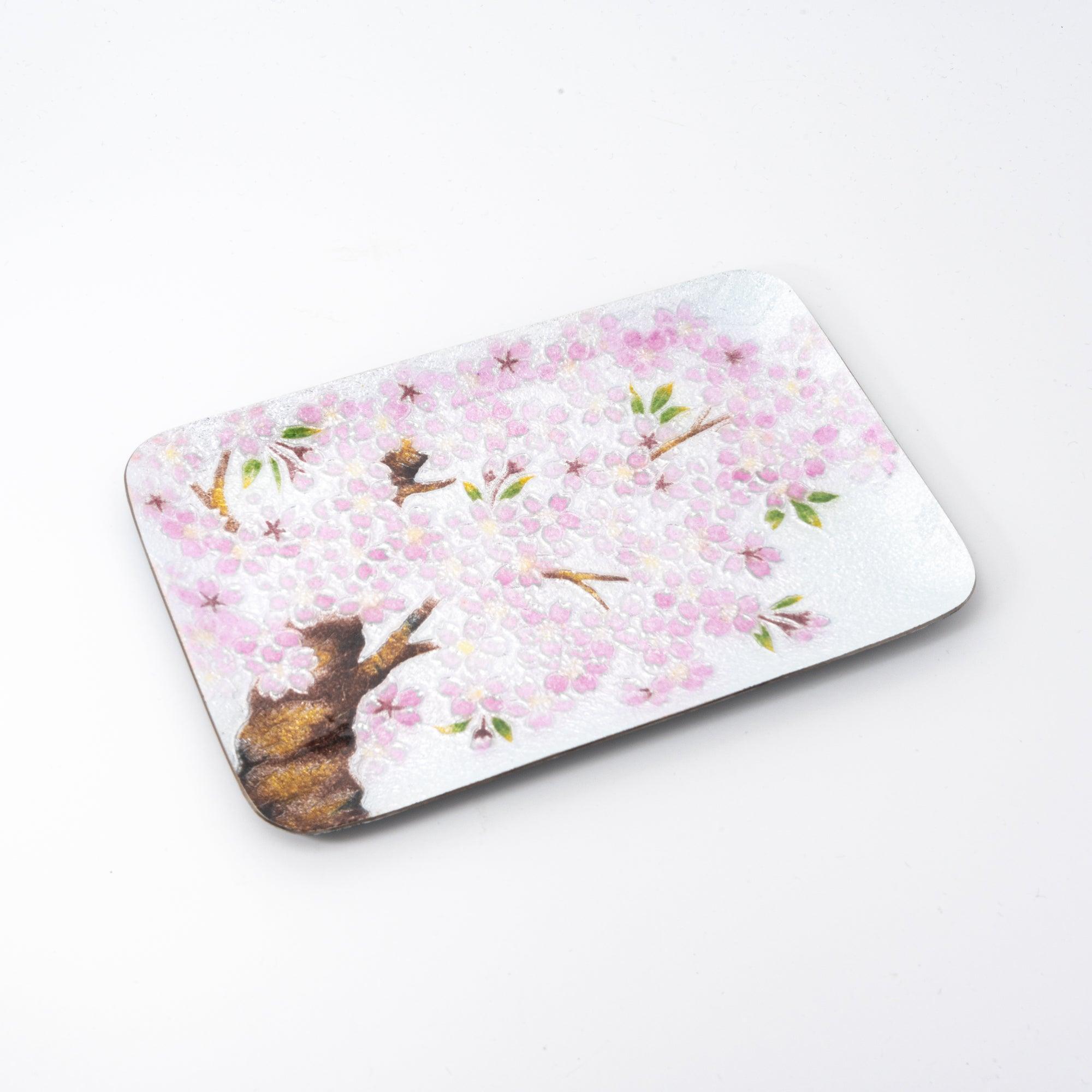 Flat view of a silver tray adorned with pink cherry blossoms and brown branches, emphasizing intricate Japanese craftsmanship.
