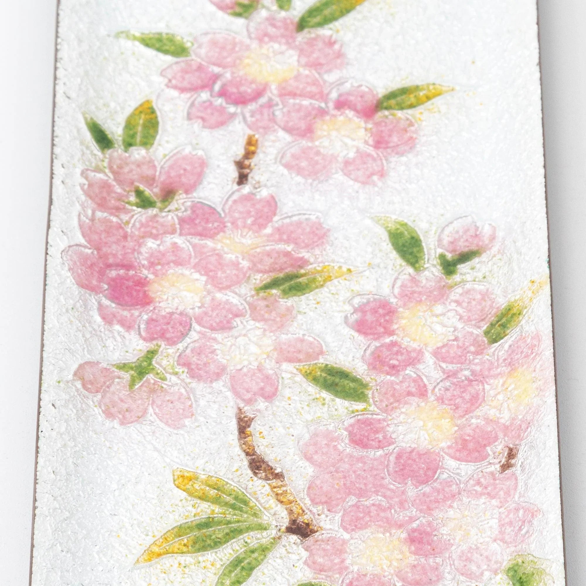 Close-up of silver enamel tray upper section showing pink sakura blossom clusters and green leaves on silver background