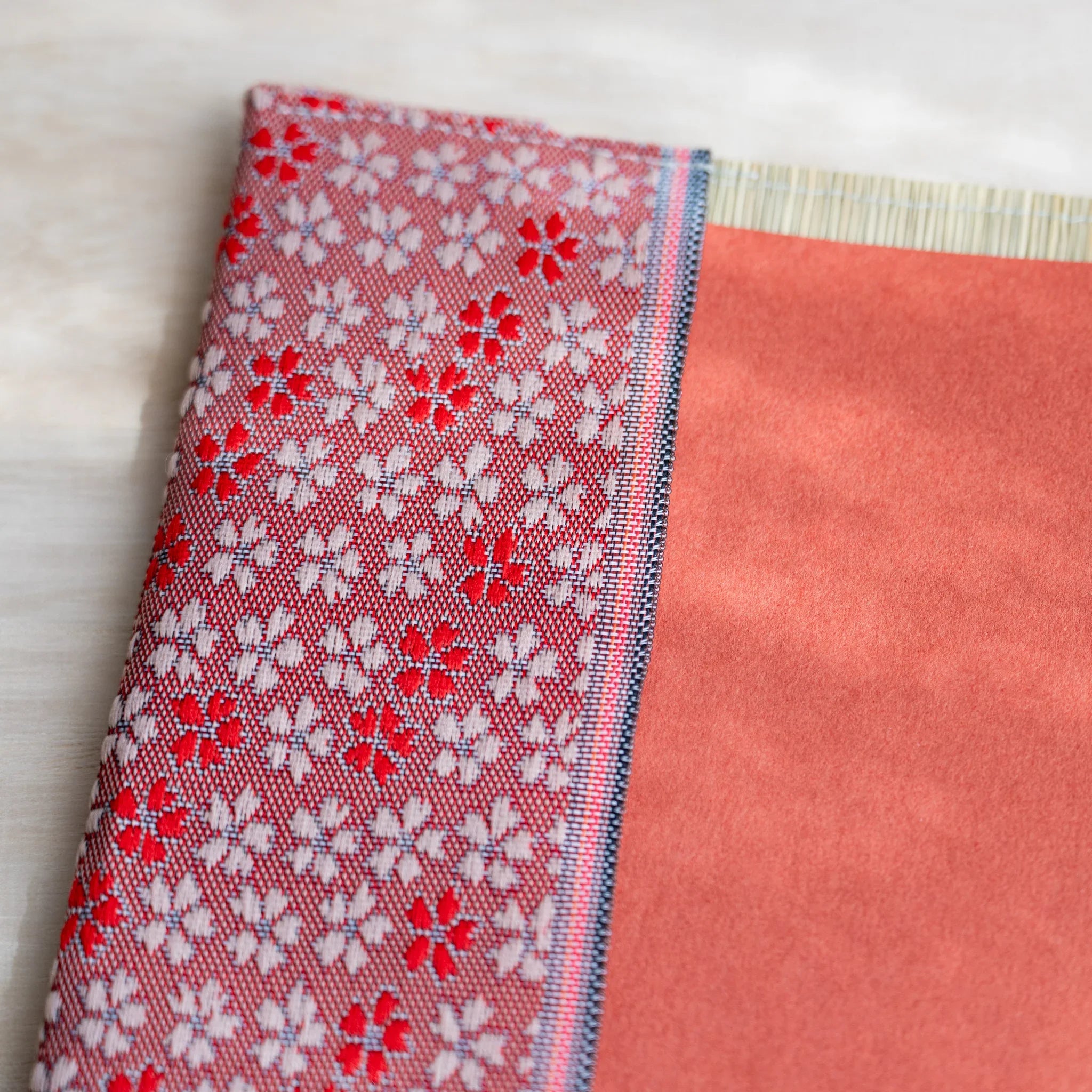 Angled close-up of the cherry blossom fabric flap folded over a coral notebook cover in the tatami book cover