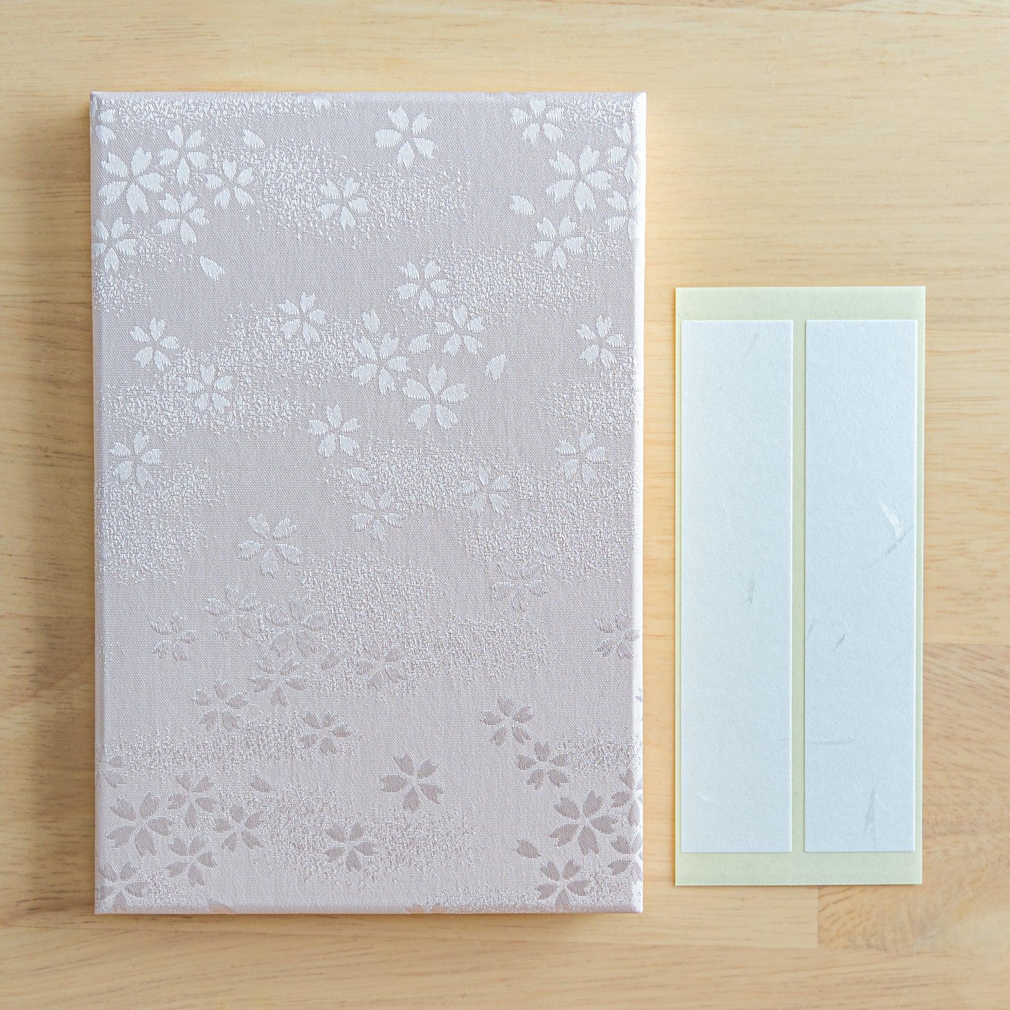 Sakura washi goshuincho front cover flat lay on wood surface beside two included cream washi name label strips