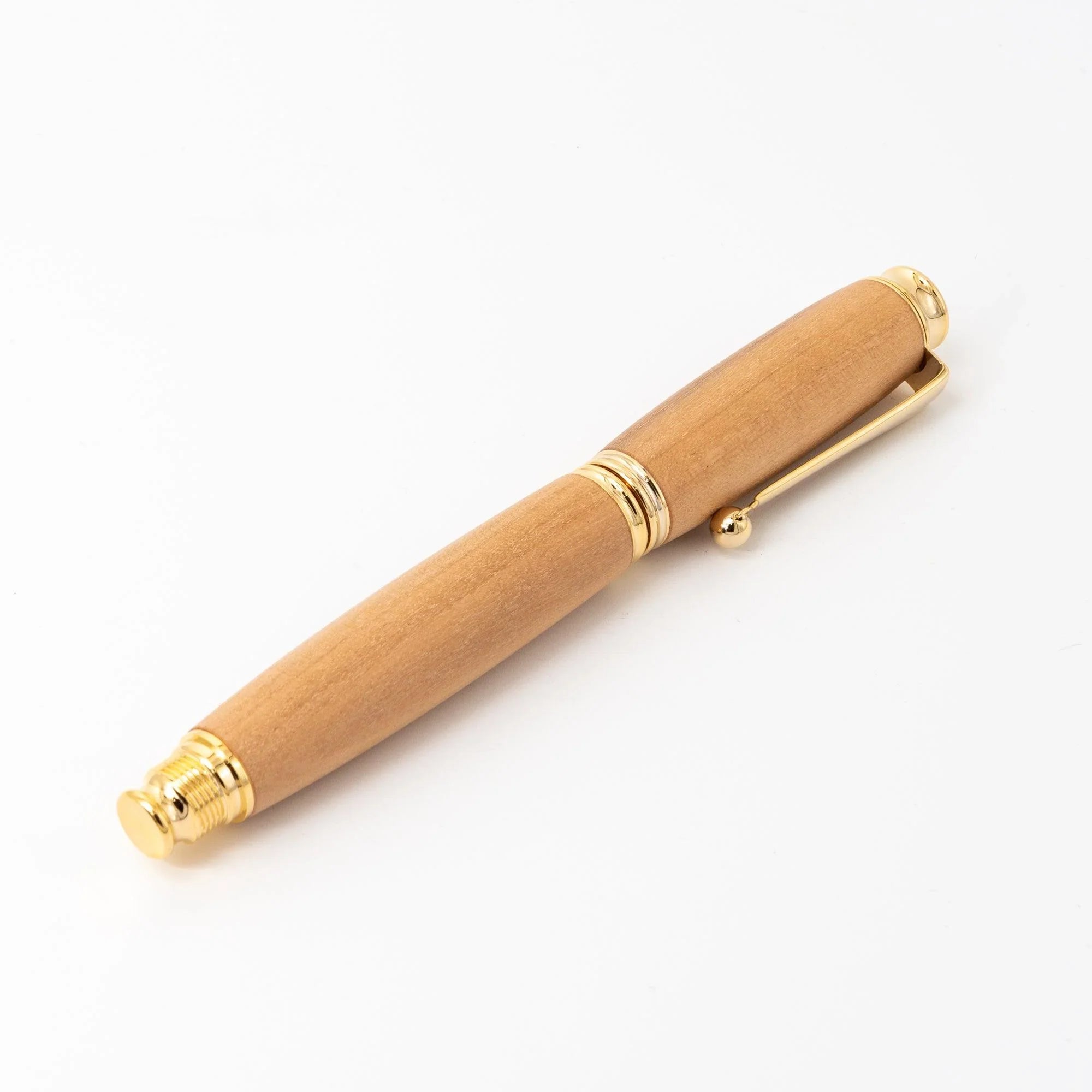Natural wood Japanese fountain pen capped on white, wood barrel with gold dome cap, trim rings, and ball-end clip