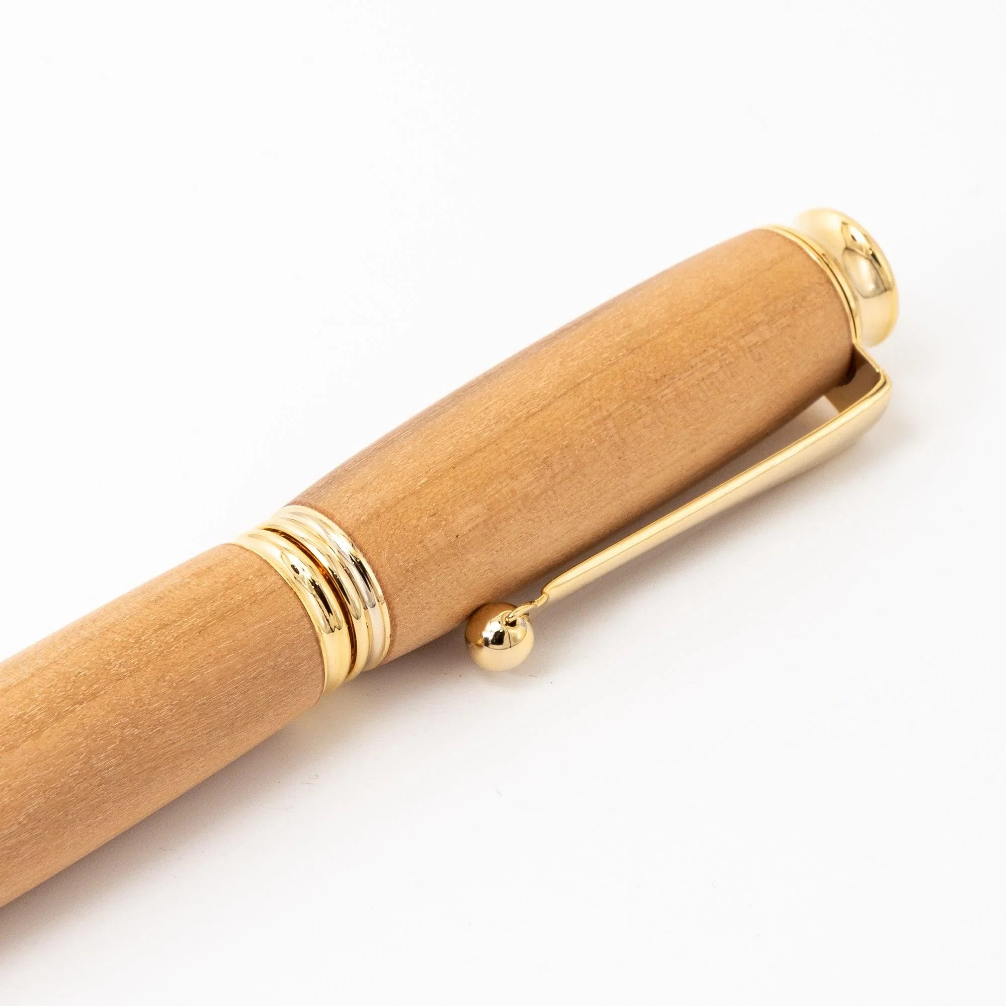 Close-up of natural wood pen cap showing wood grain, gold dome top, trim ring, and ball-end clip on white background