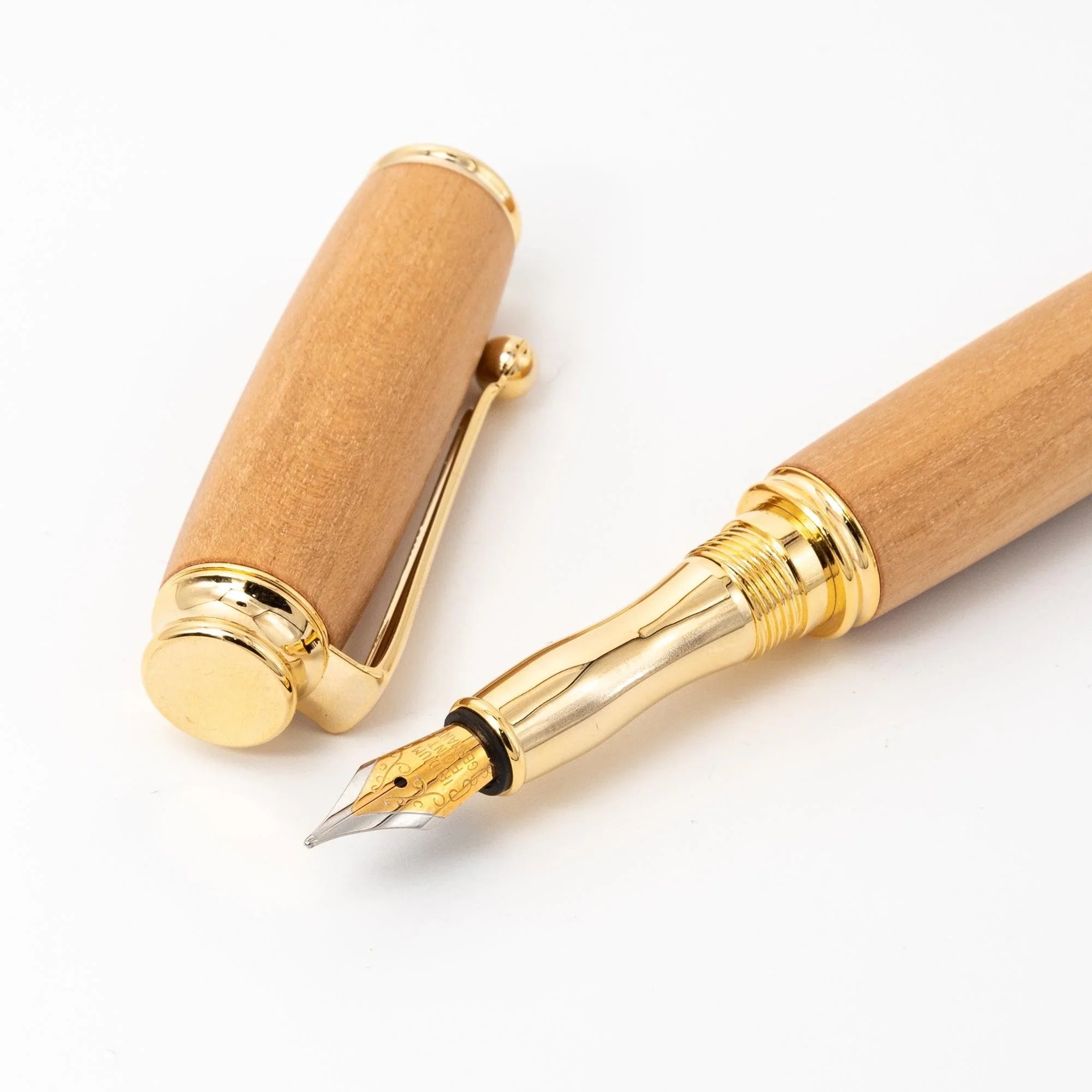 Natural wood Japanese fountain pen uncapped, cap and barrel separated on white surface showing gold nib and cap with clip