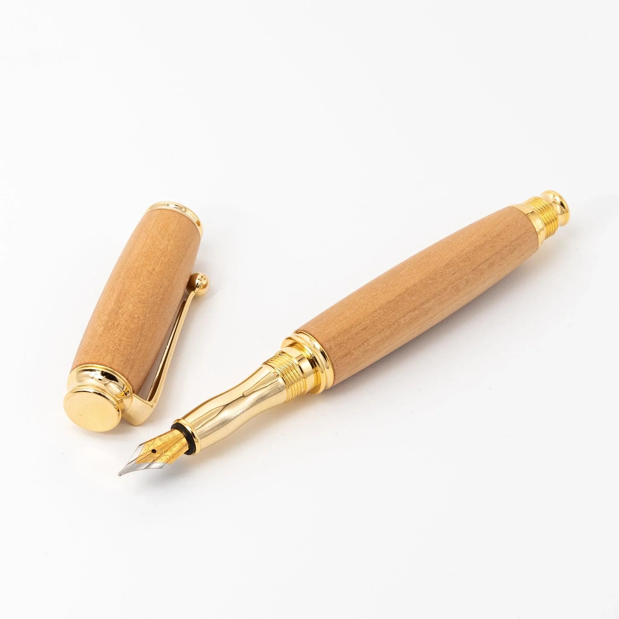 Natural wood Japanese fountain pen disassembled on white, barrel showing gold nib and section, cap with dome and clip