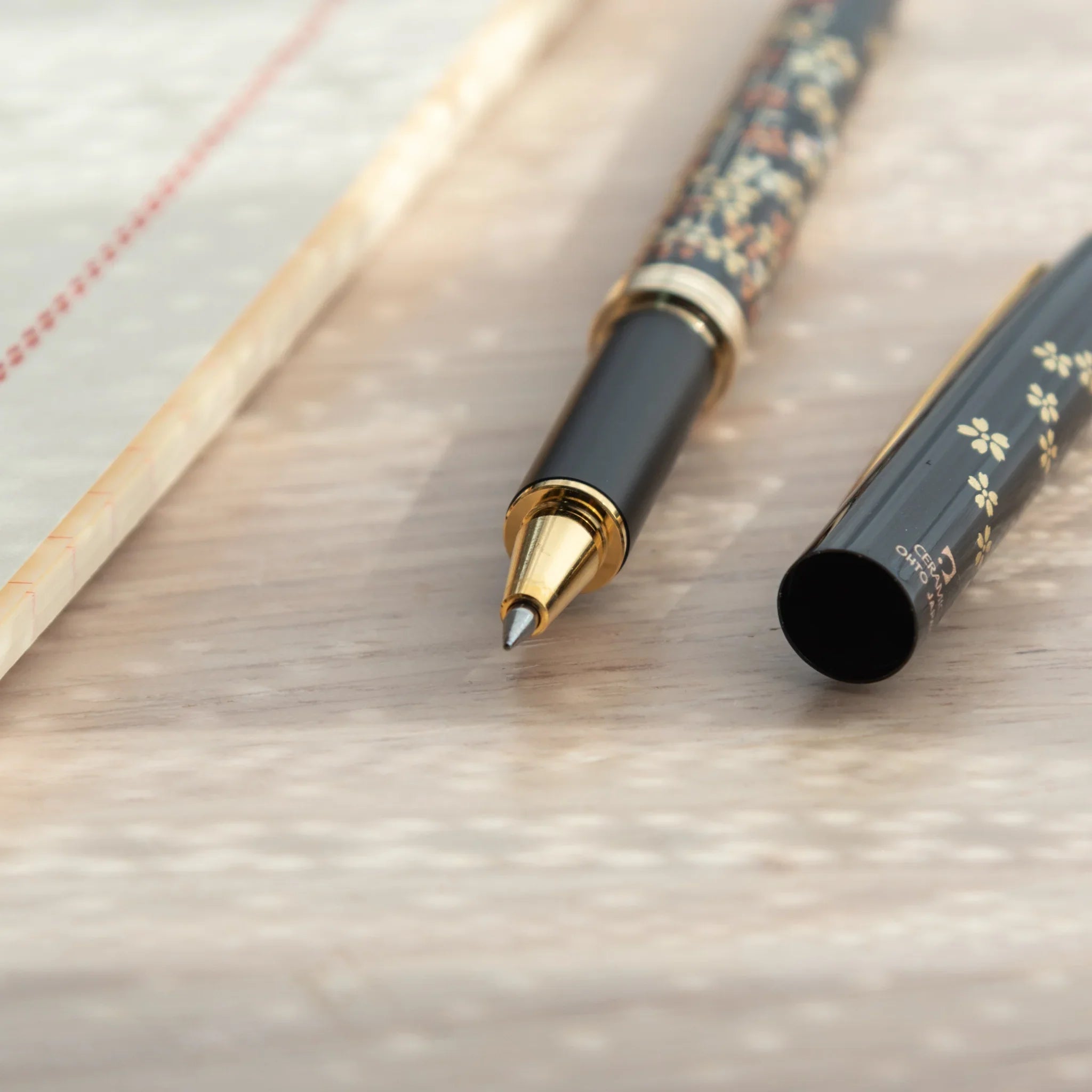 Capped-off Japanese Ballpoint Pen with Lacquer finish, featuring sakura design on a black glossy body.