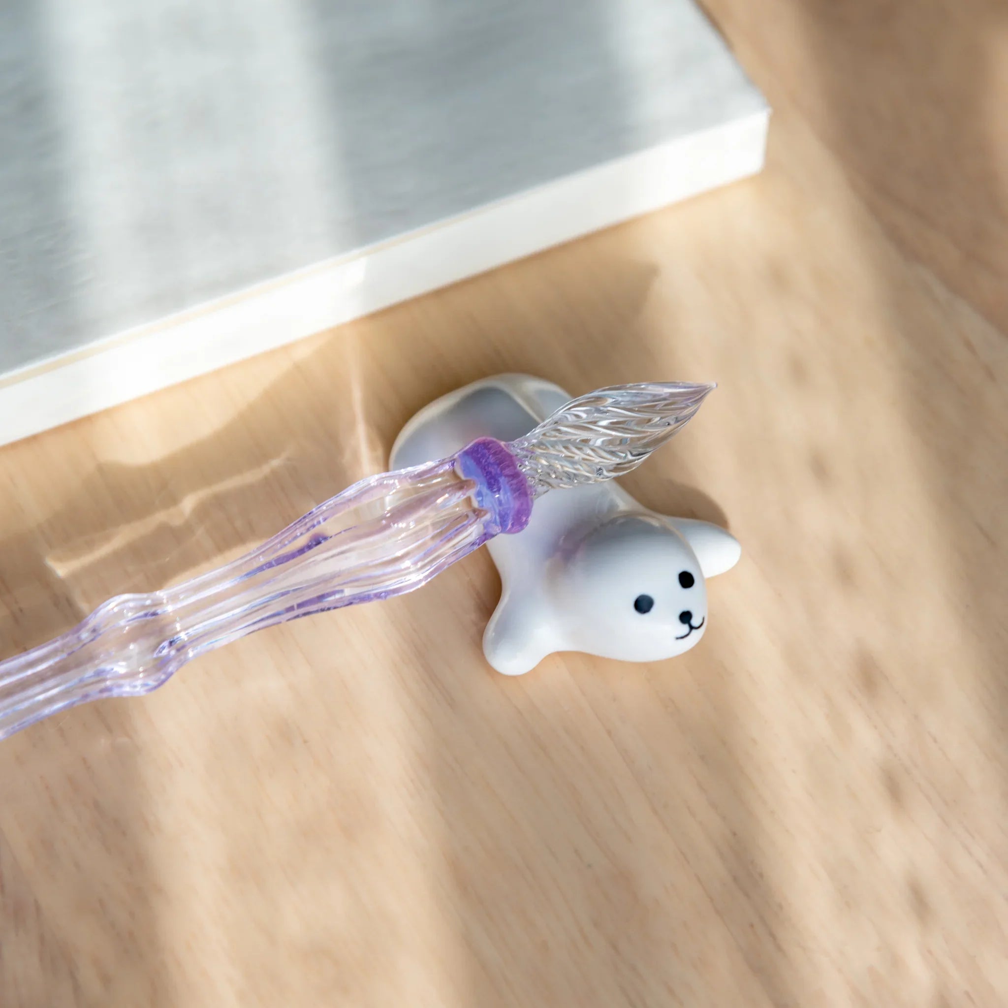 Gray ceramic seal-shaped handcrafted pen rest featuring animal likeness and smooth grooved pen holder close shot