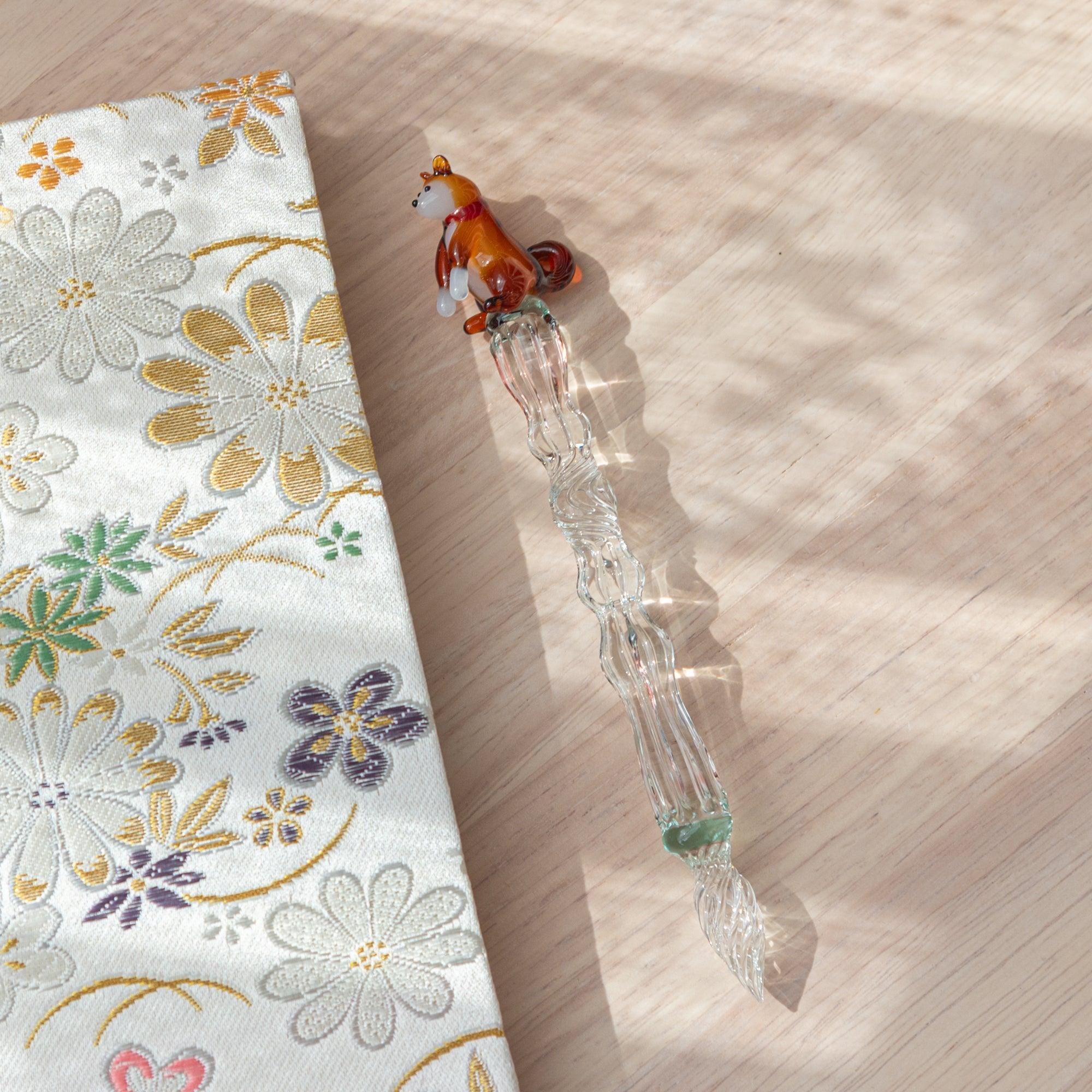 Japanese Shiba Inu glass dip pen with textured ribbed glass barrel and ceramic dog topper, minimalist product shot