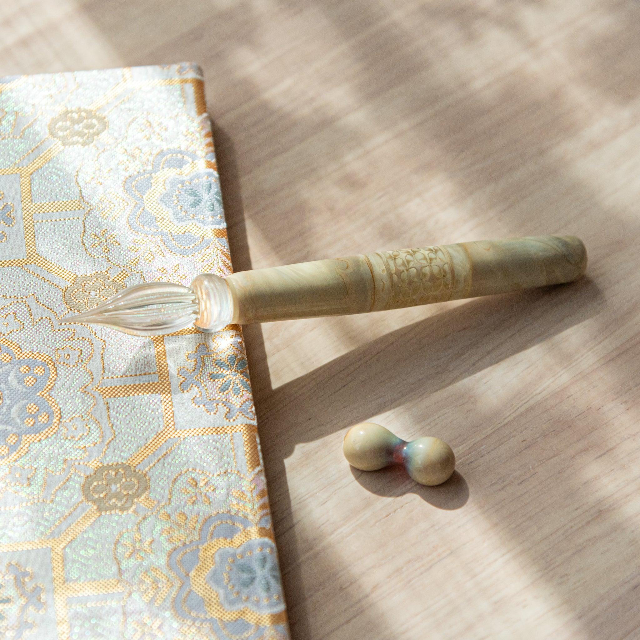 Top view of shippo wooden dip pen with decorative fabric background highlighting engraved shippo pattern in frame