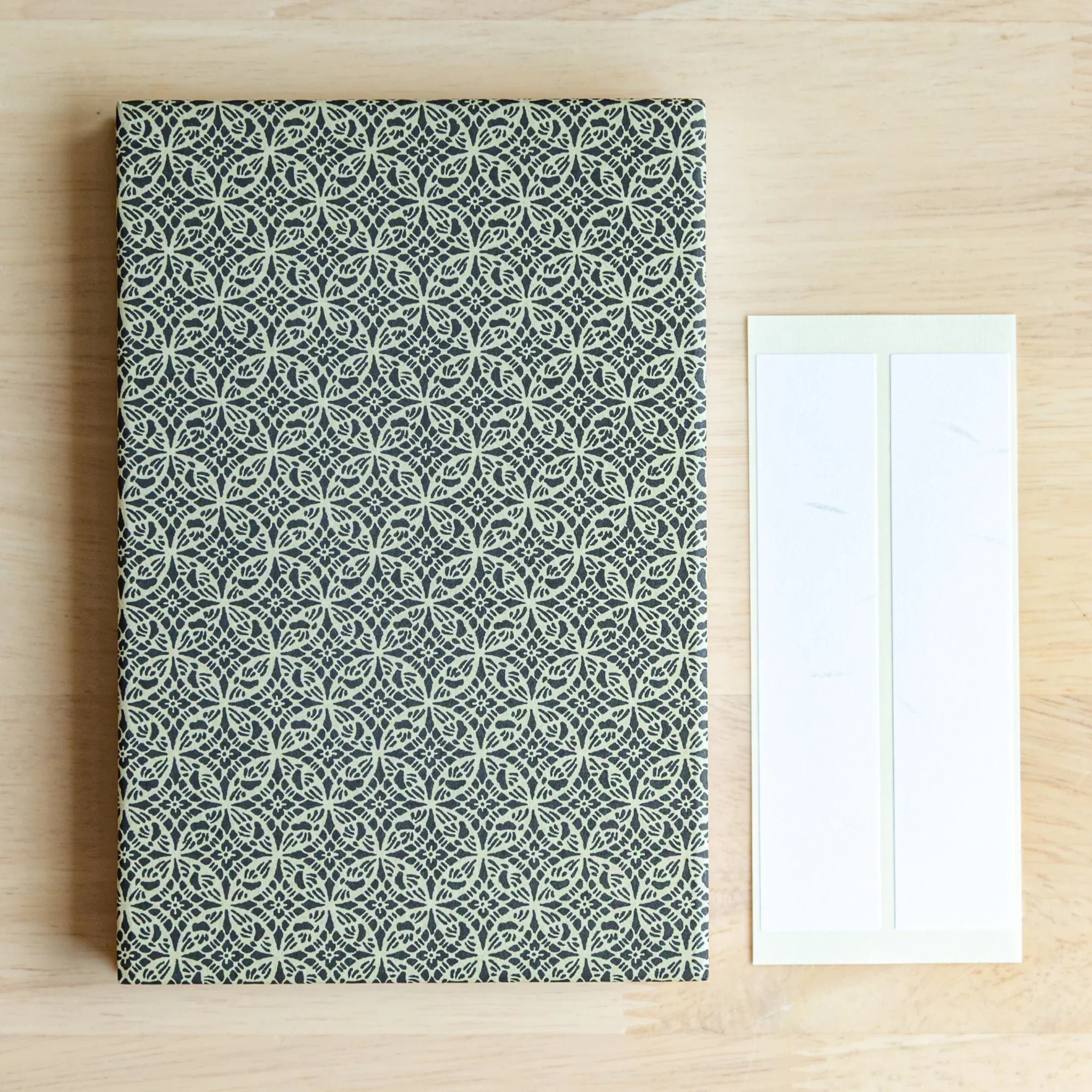 Shippo Pattern washi goshuincho front cover flat lay on wood surface beside two included cream washi name label strips