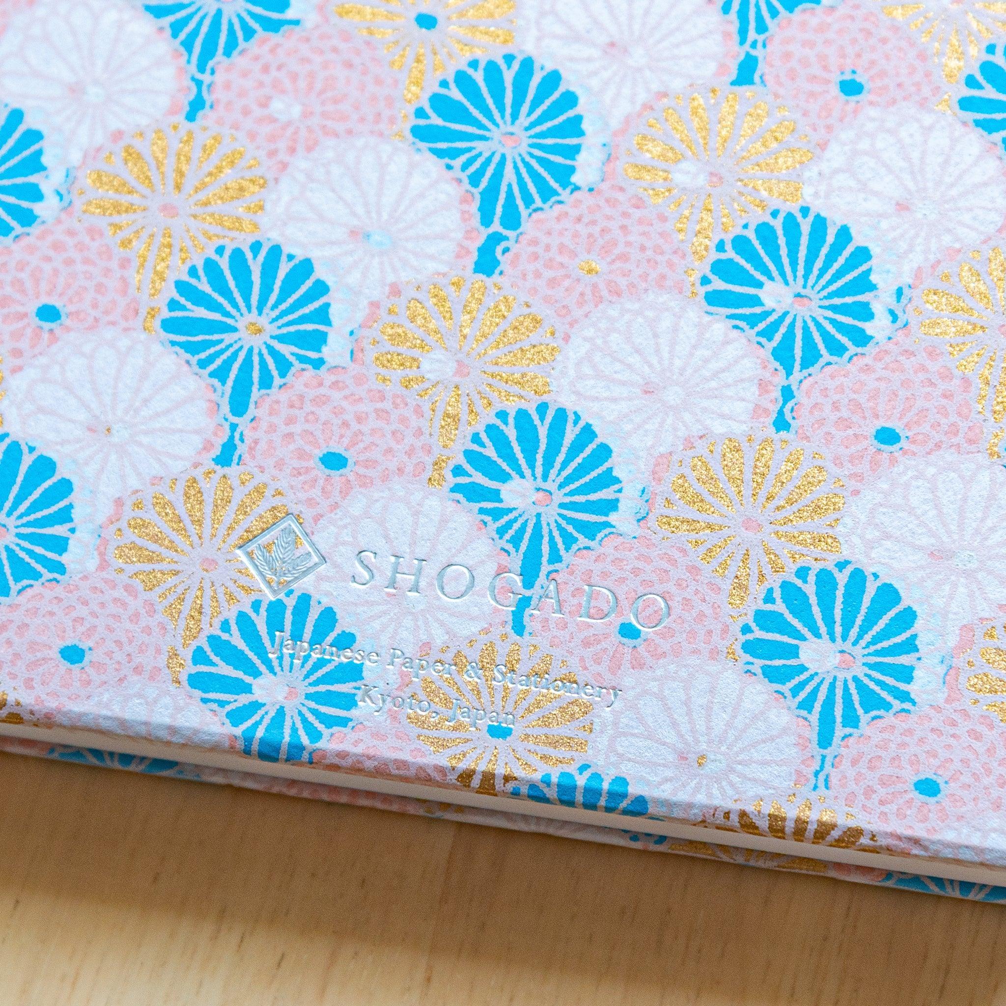Close-up of pastel chrysanthemum pattern on Goshuinsho stamp book by SHOGADO, Japanese stationery brand.