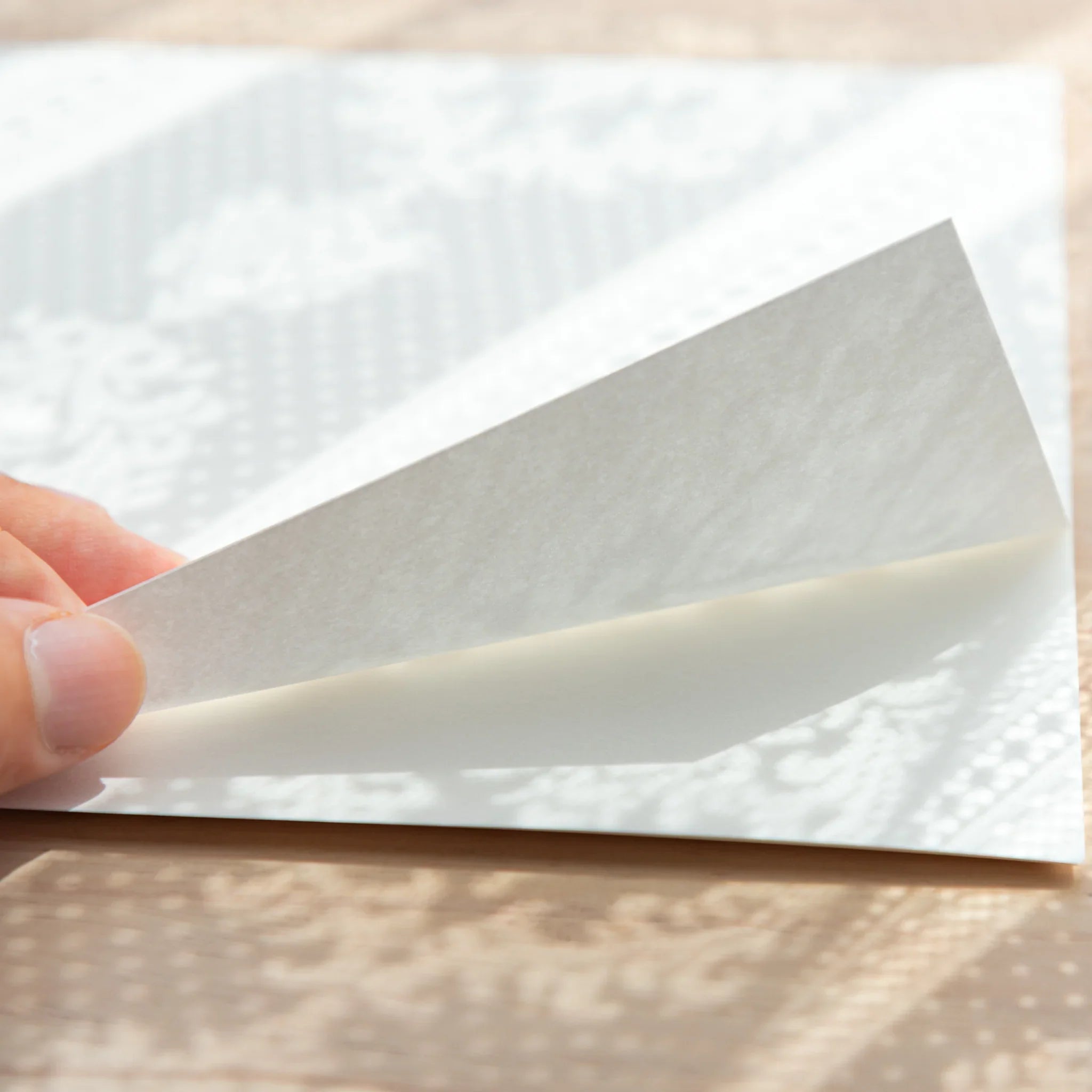 Slightly bent Smooth Onion Skin sheet with lace patterns faintly visible through its translucency.