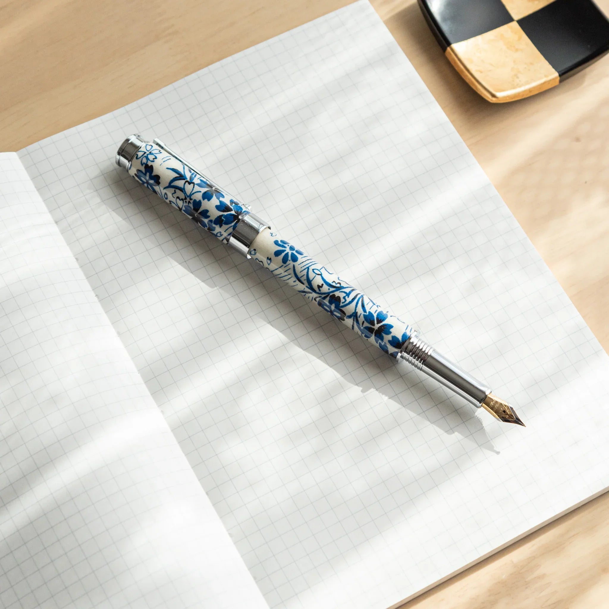 Streaming Sakura fountain pen barrel section with white and blue flowing cherry blossom design on navy Mino washi wrapper