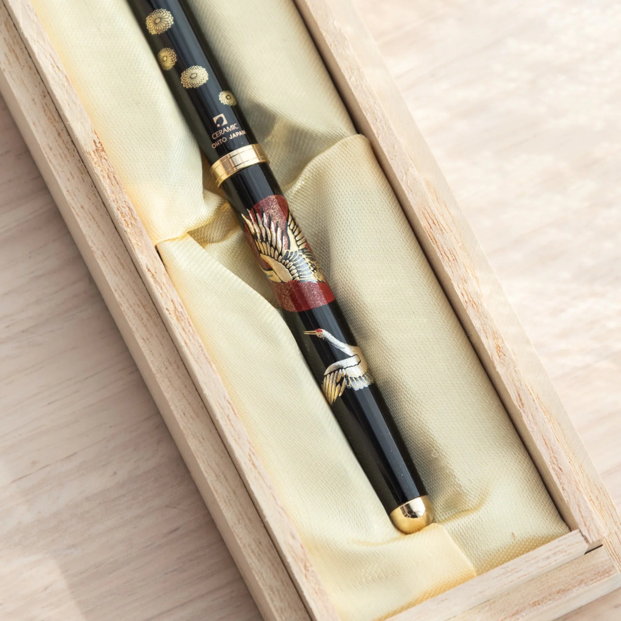 Close-up of a Japanese Ballpoint Pen featuring Lacquer artwork of cranes and red sun in a box with golden satin.