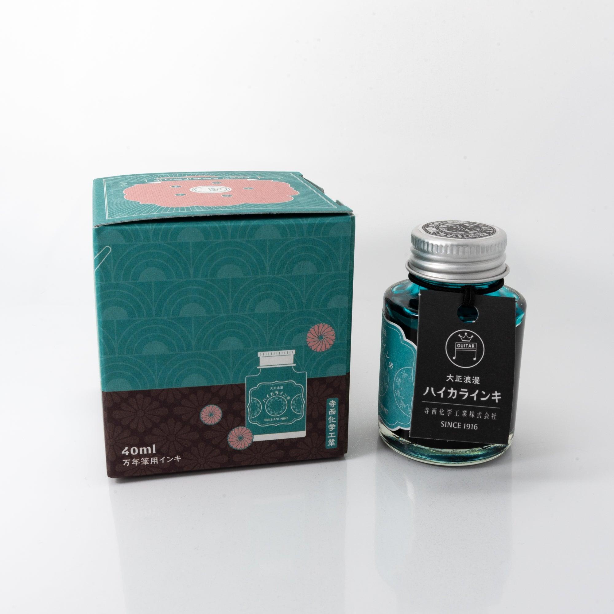 Open Taisho Romance Brilliant Mint ink bottle with radiant mint liquid, placed beside a fountain pen, blending style and usability.