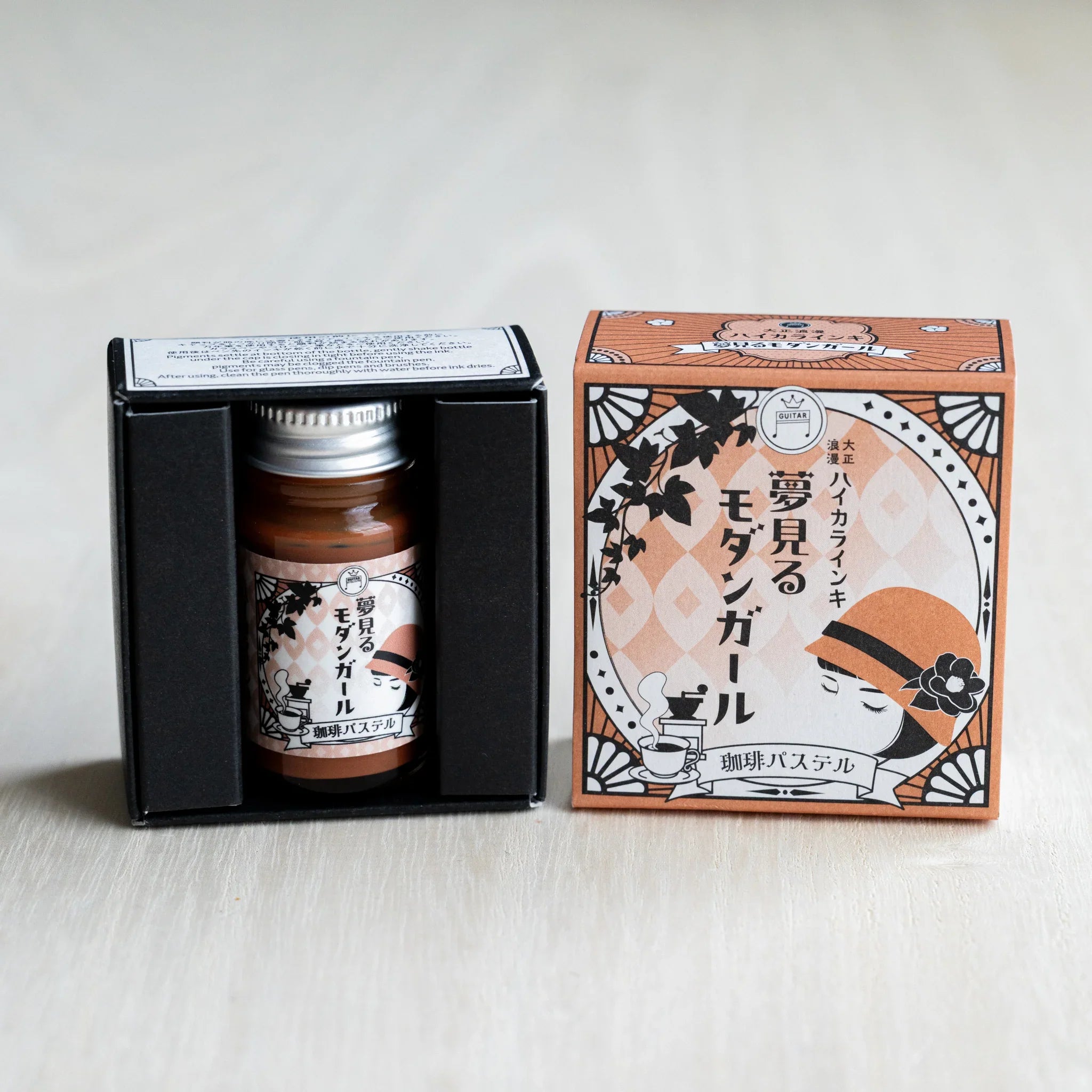 Taisho Romance Coffee Pastel ink bottle in its open black inner box, next to the closed tan outer box