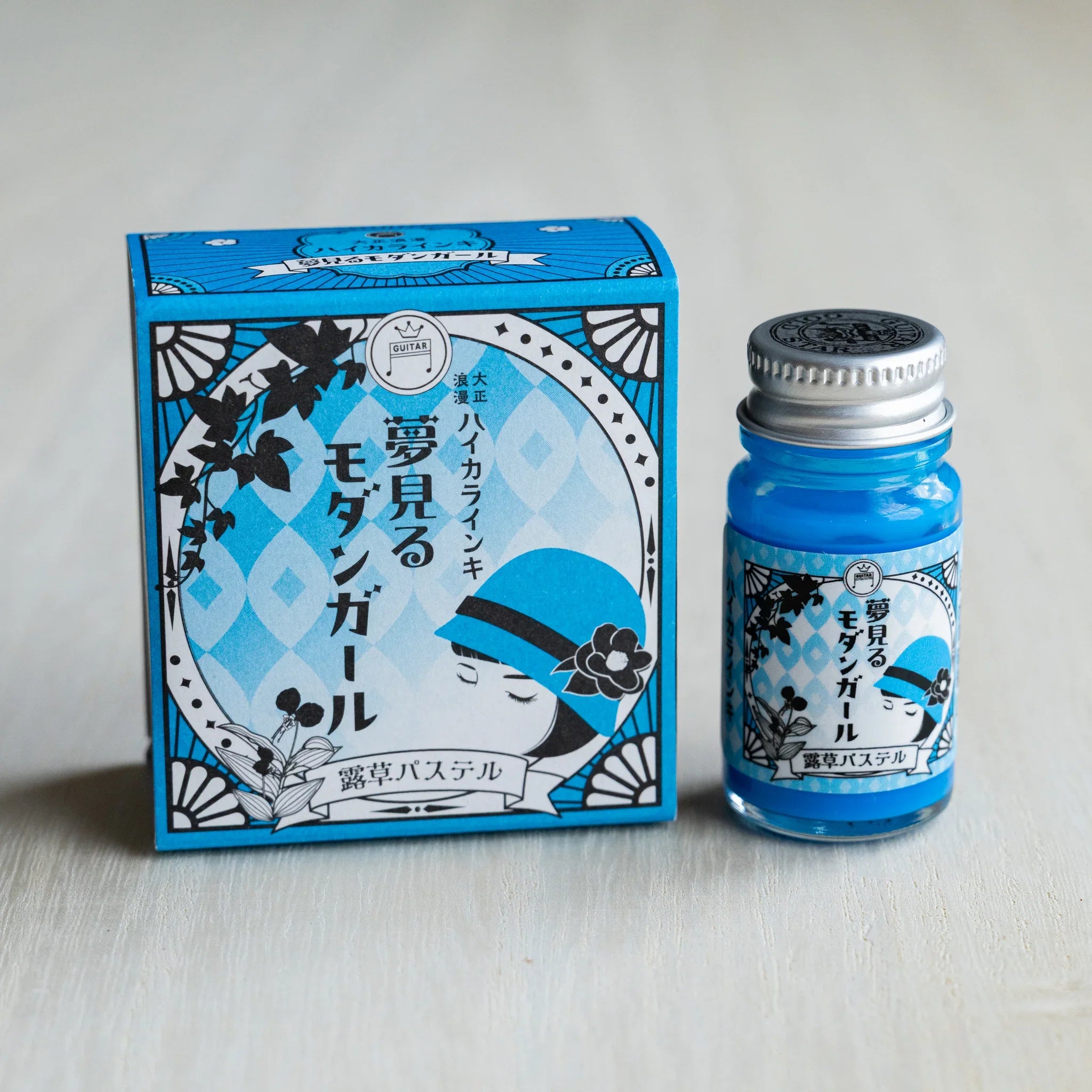Taisho Romance Dayflower Pastel ink box in cyan blue beside a 12 ml glass bottle of opaque cyan blue pigment ink