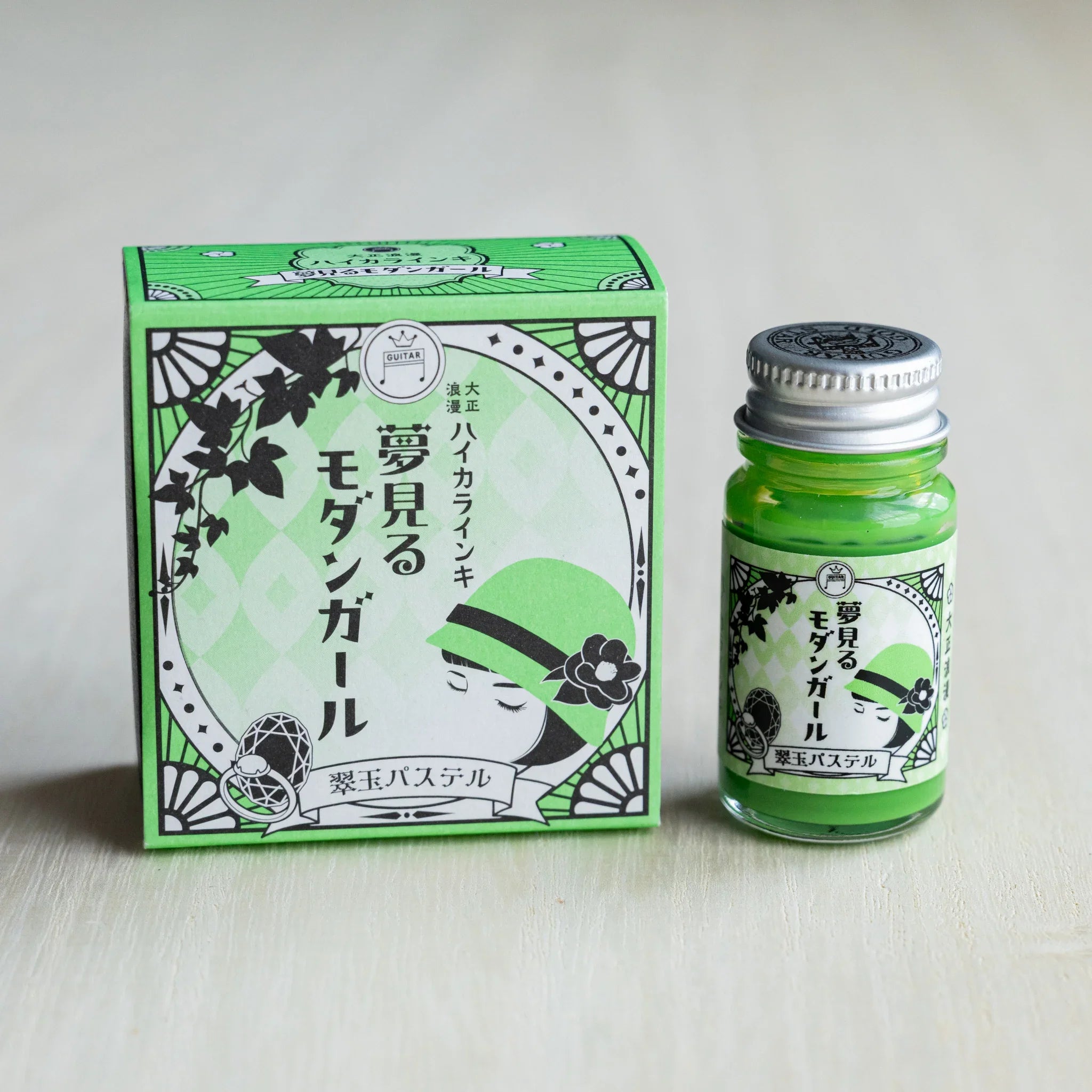 Taisho Romance Jade Pastel ink box in green beside a 12 ml glass bottle of opaque grass green pigment ink
