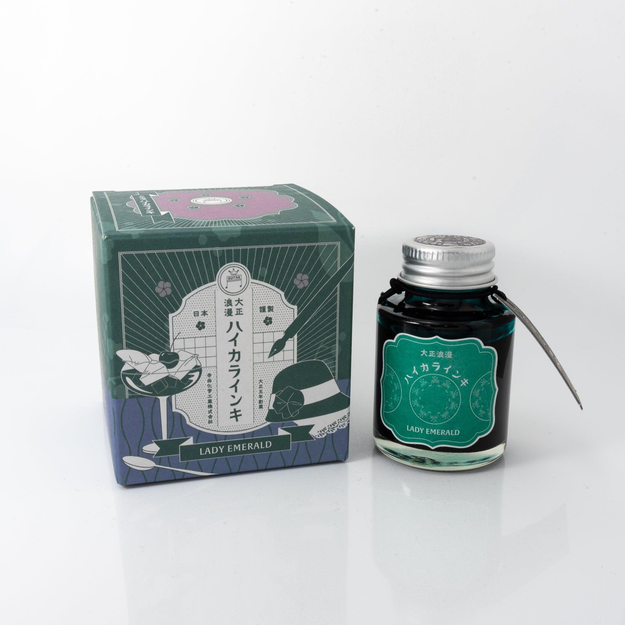Taisho Romance Lady Emerald fountain pen ink bottle with a rich green hue, placed on a wooden desk under soft natural light.