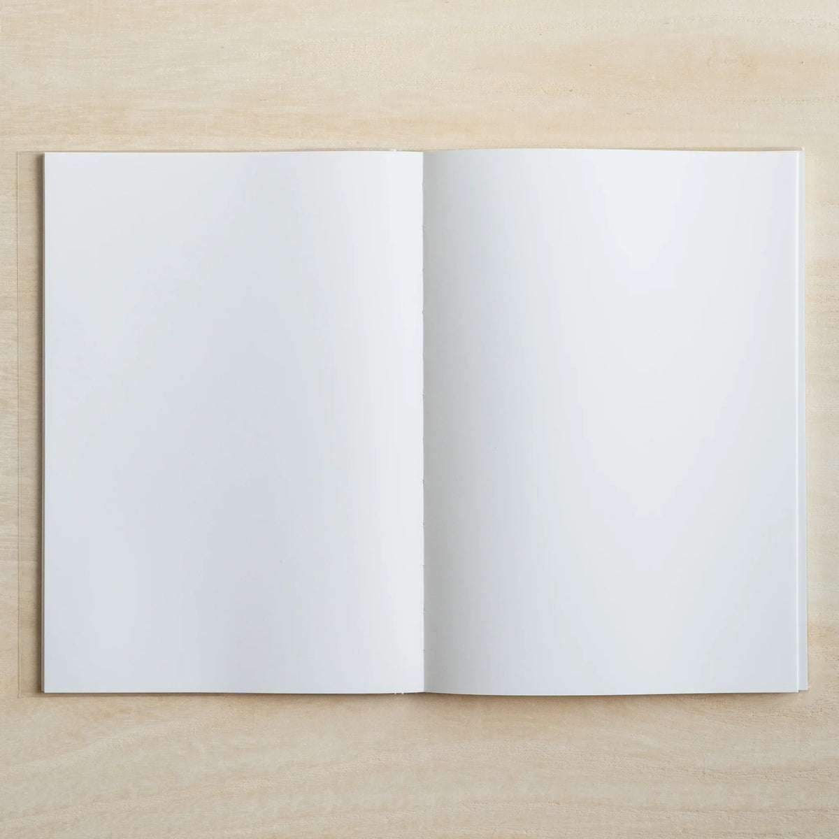 HAIKARA notebook open flat to a blank white page spread on a pale wood surface