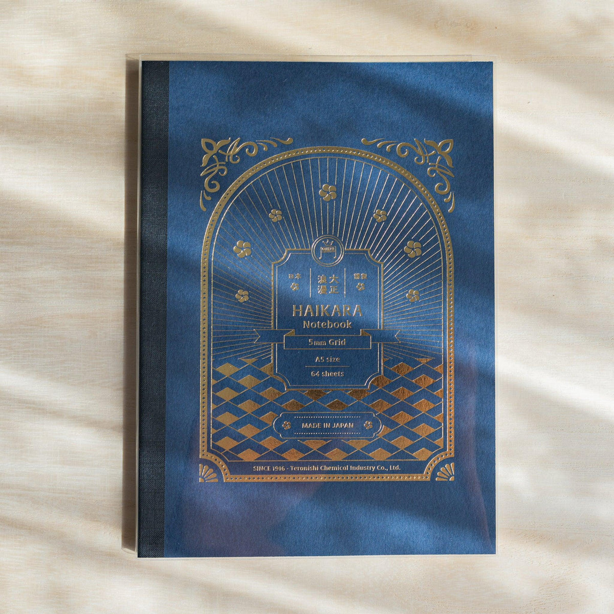 Dark blue HAIKARA notebook cover with gold foil arch frame, flower motifs and diamond lattice pattern, cloth spine tape